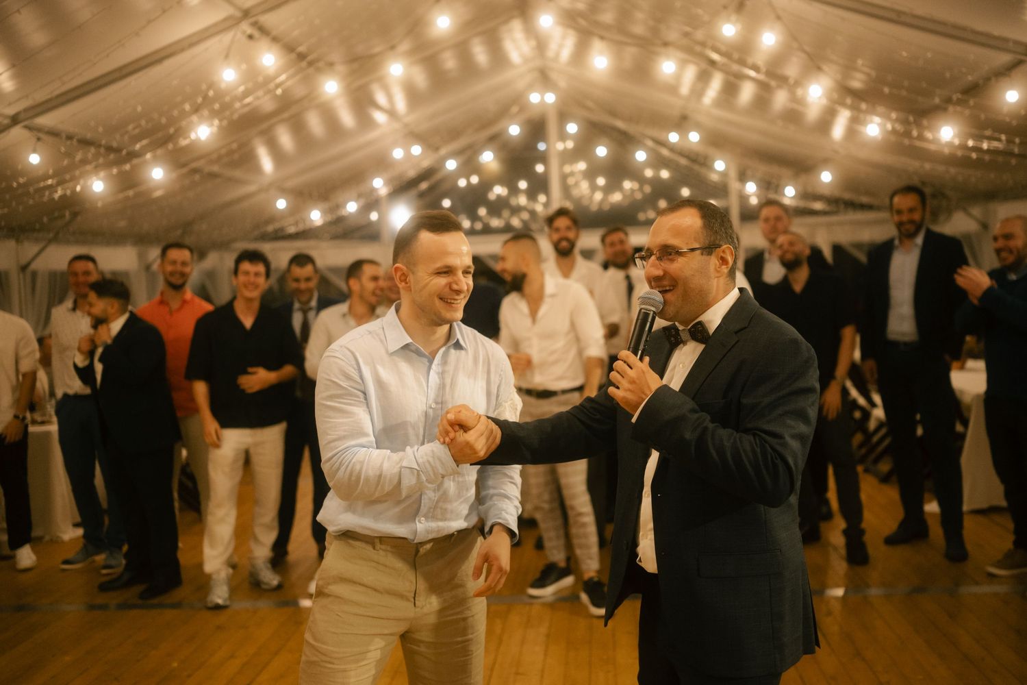 Dancers move across a wooden dance floor under warm lighting at an indoor social gathering event.