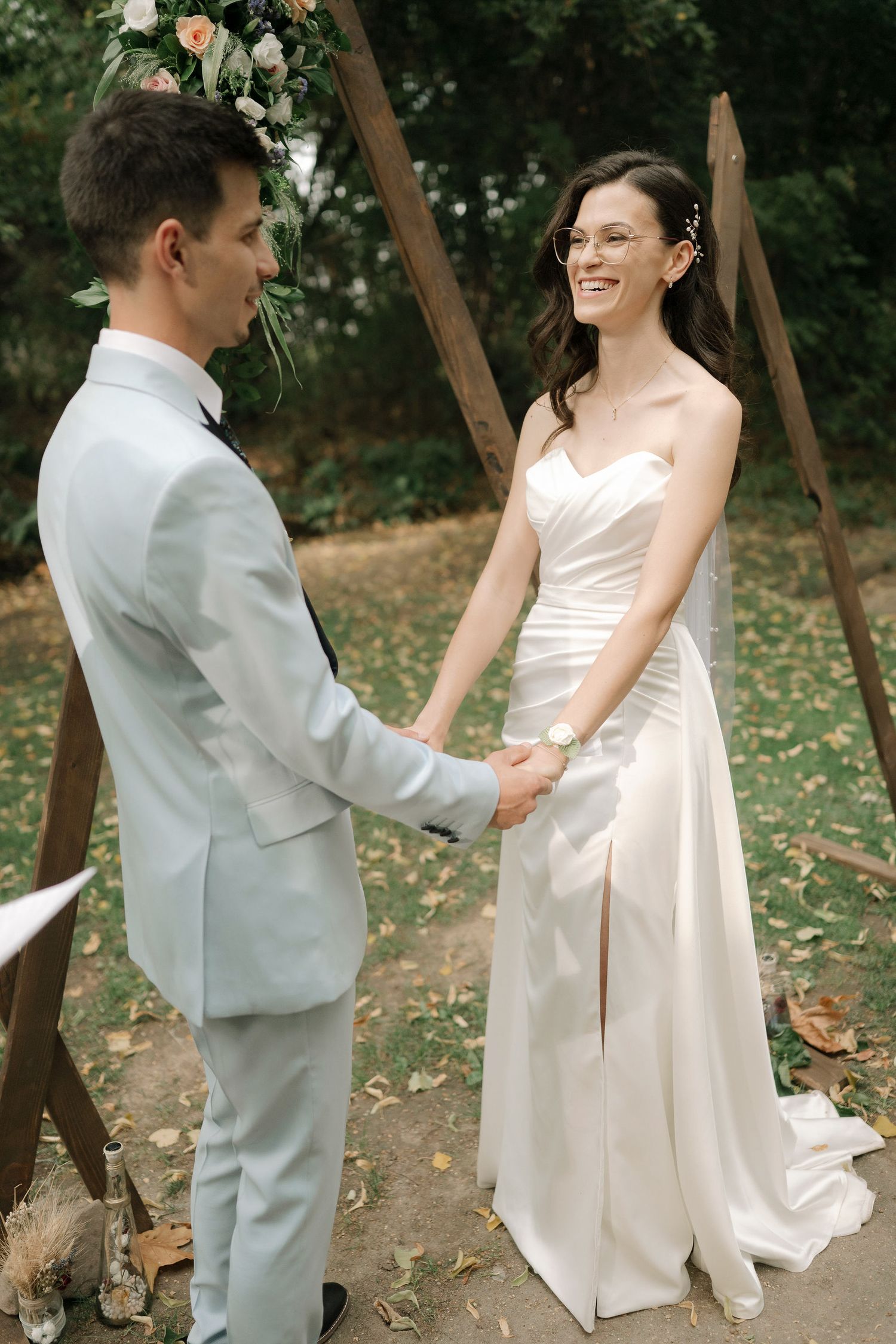A couple shares a joyful moment together on their wedding day in an outdoor garden setting with wooden beams.
