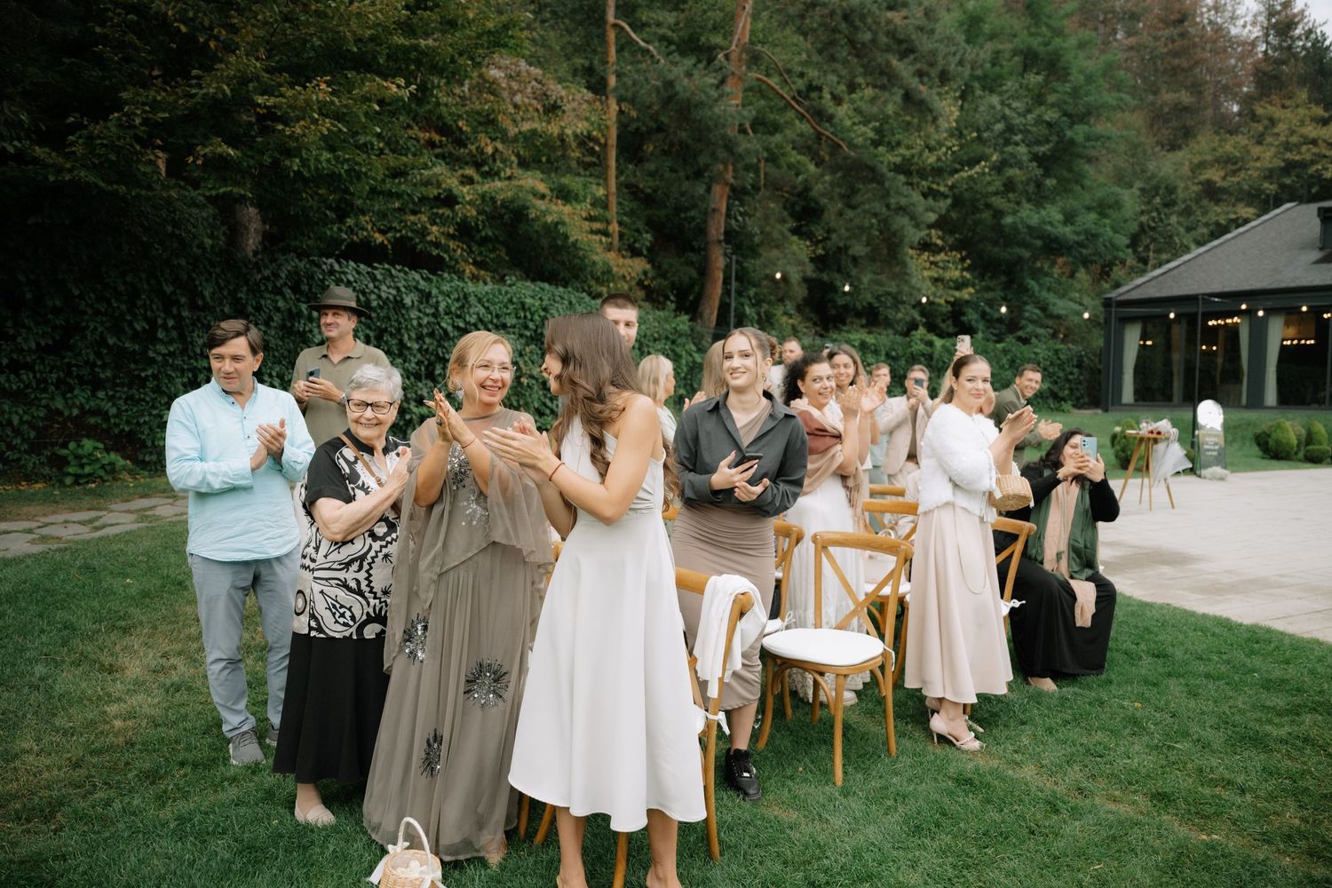 A series of outdoor wedding celebration photos showing guests in neutral tones and white dresses gathered in a garden setting.