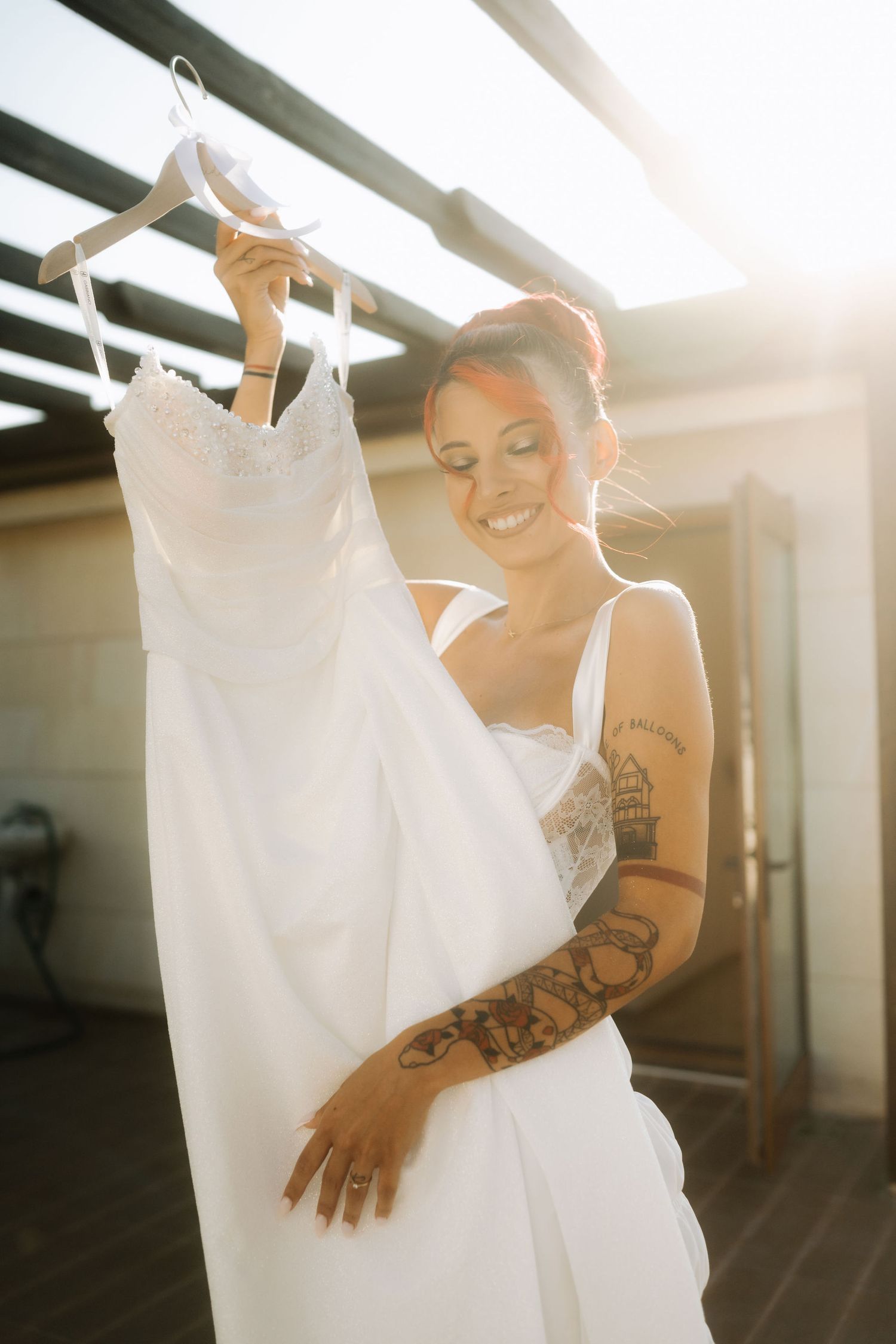 A series of sunlit photos showing a white dress hanging while someone with tattoos interacts with it.