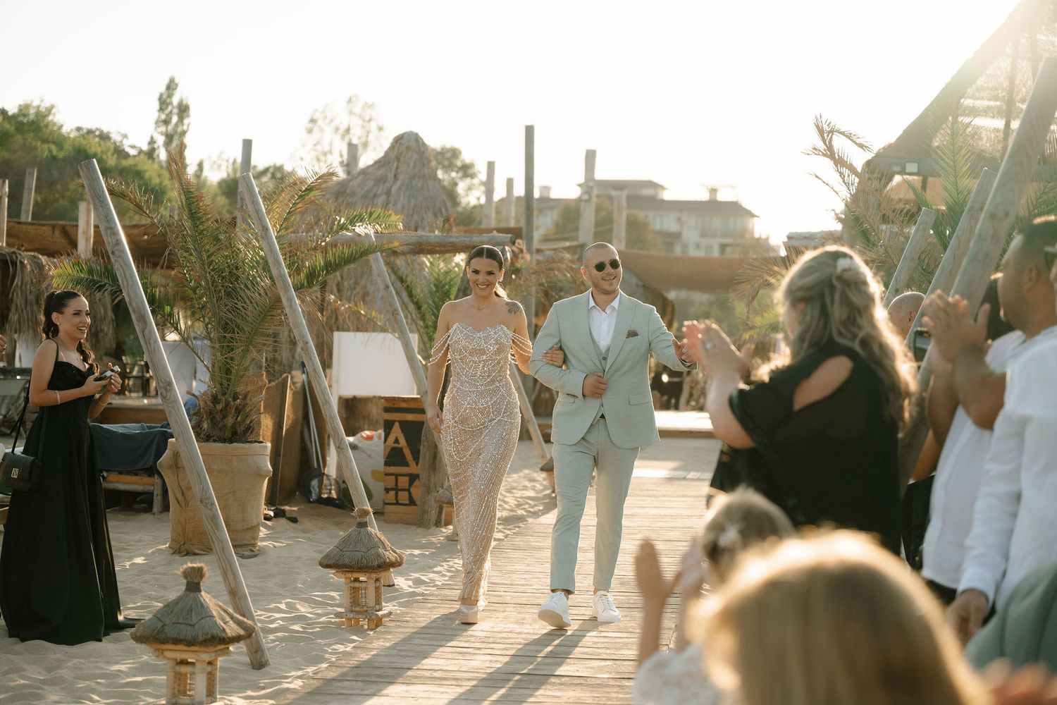 Wedding guests dance and celebrate during a golden hour outdoor reception at a beachside venue.