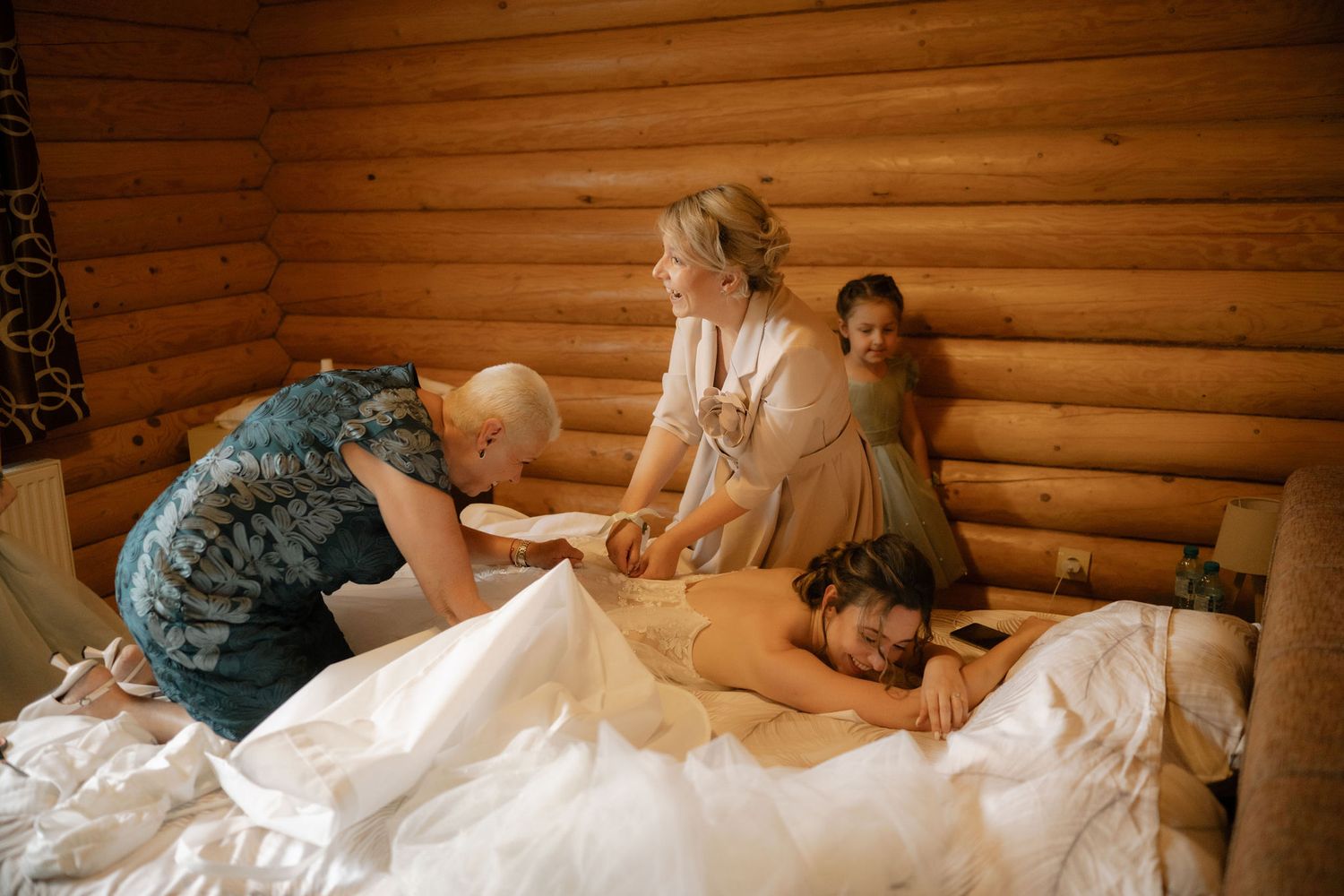A group of people work together to fold and prepare white linens in a rustic log cabin setting.