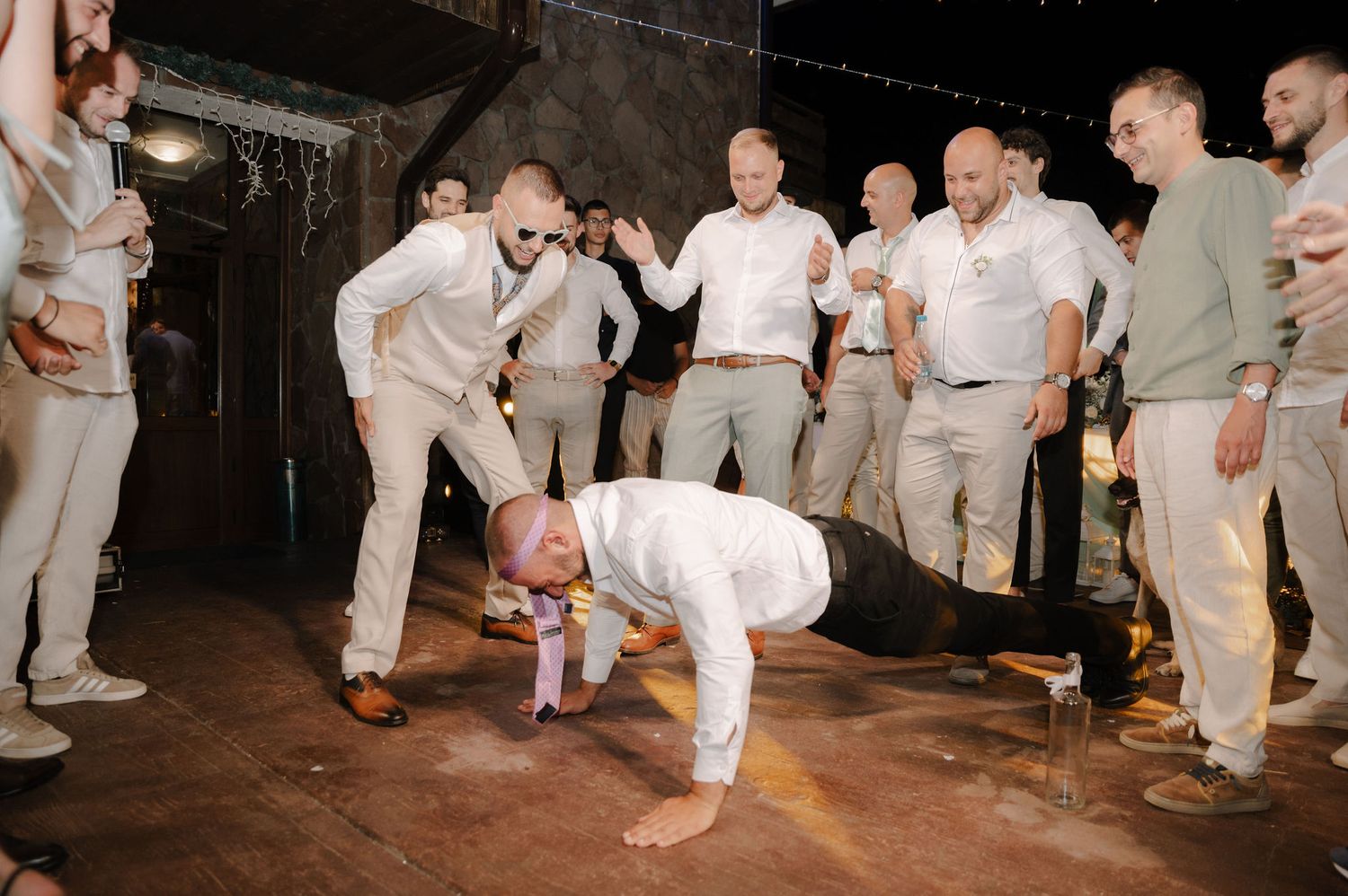 Capoeira performers in white uniforms demonstrate martial arts moves in a dimly lit performance space.