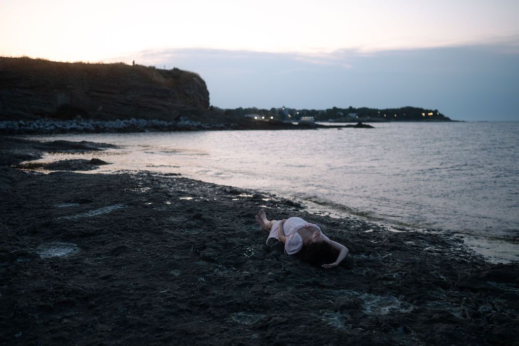 A serene coastal landscape with rocky shores and gentle waves rolling in at sunset.