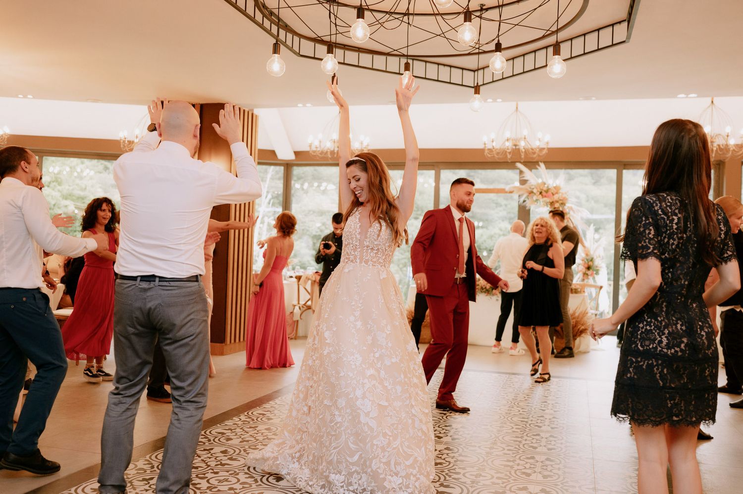 Couples practicing dance moves together in a bright dance studio with wooden floors and chandeliers.