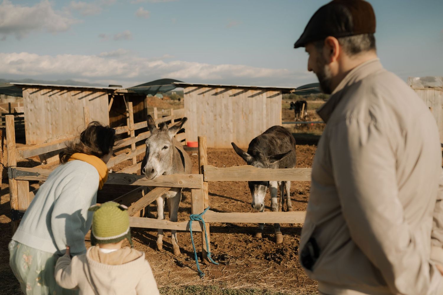 People working outdoors in a rural setting with wooden structures and farm equipment visible in the background.