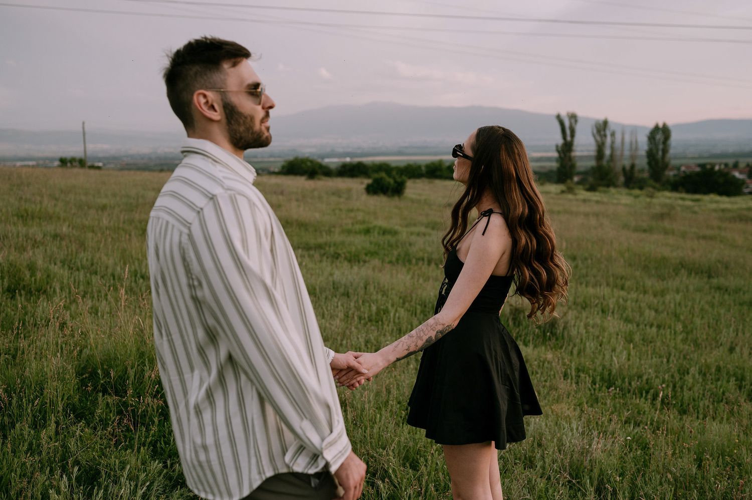 A couple in a grassy meadow at sunset share intimate moments across a series of romantic photographs.