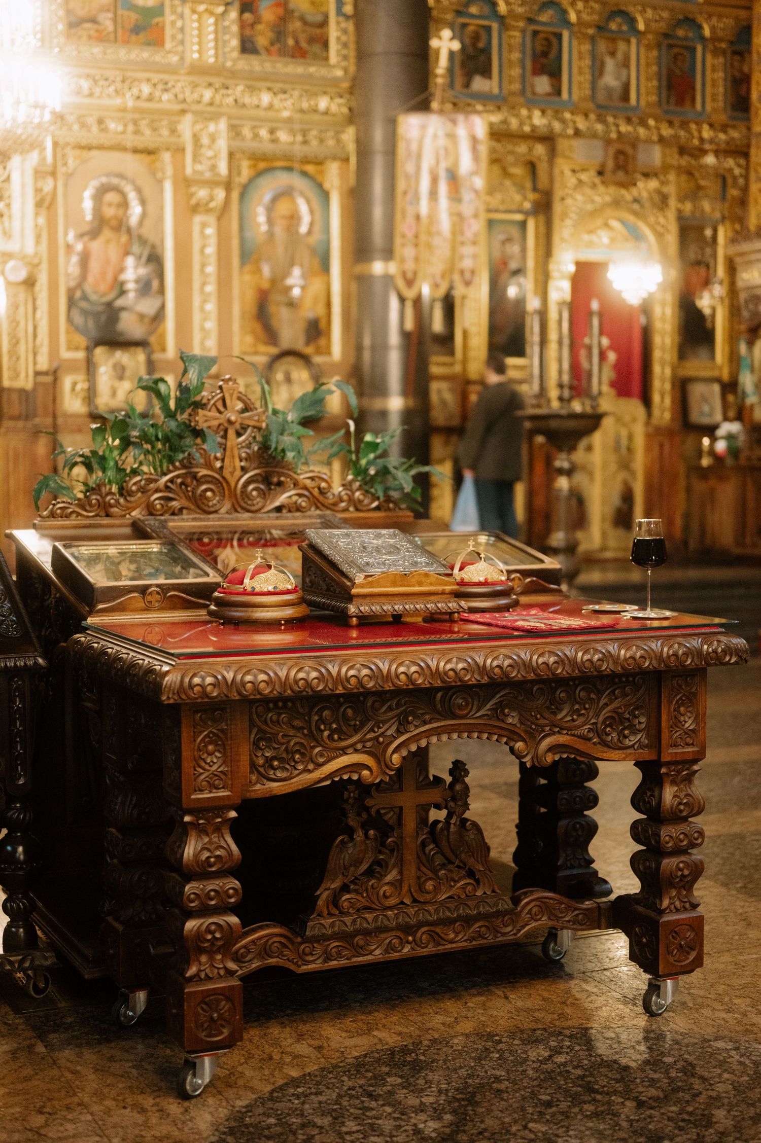 Ornate antique wooden table with intricate carvings and dark finish displayed in an opulent church or cathedral interior.