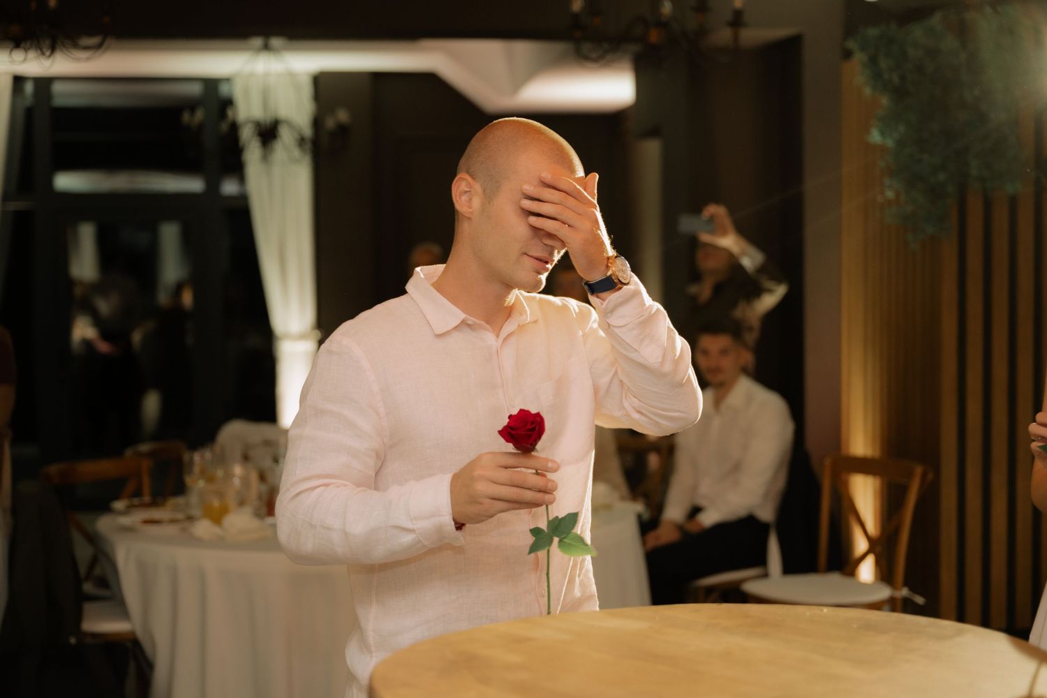 A couple celebrates at their wedding reception, with one person wearing a white dress and another in a white suit.