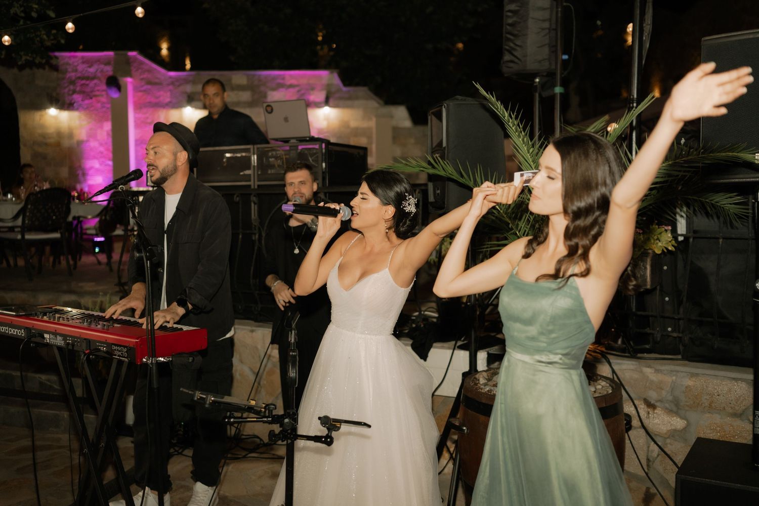 Wedding guests dance together on a dimly lit dance floor with purple lighting and festive atmosphere.