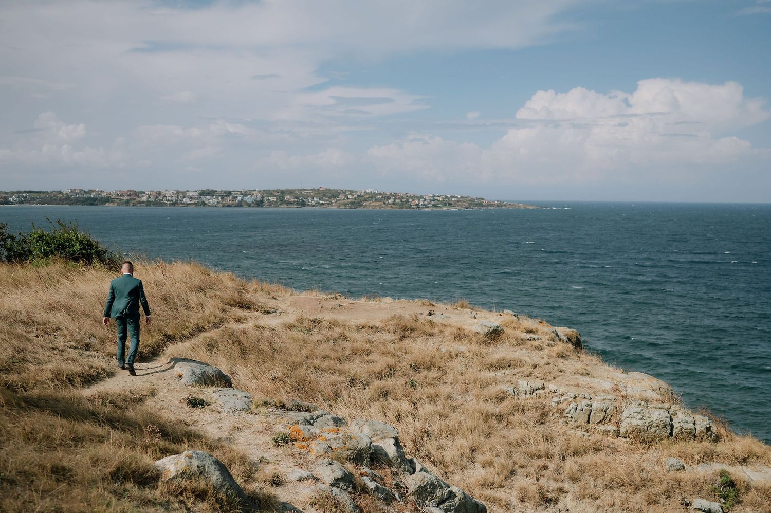 Panoramic coastal landscape with grassy cliffs overlooking the ocean.