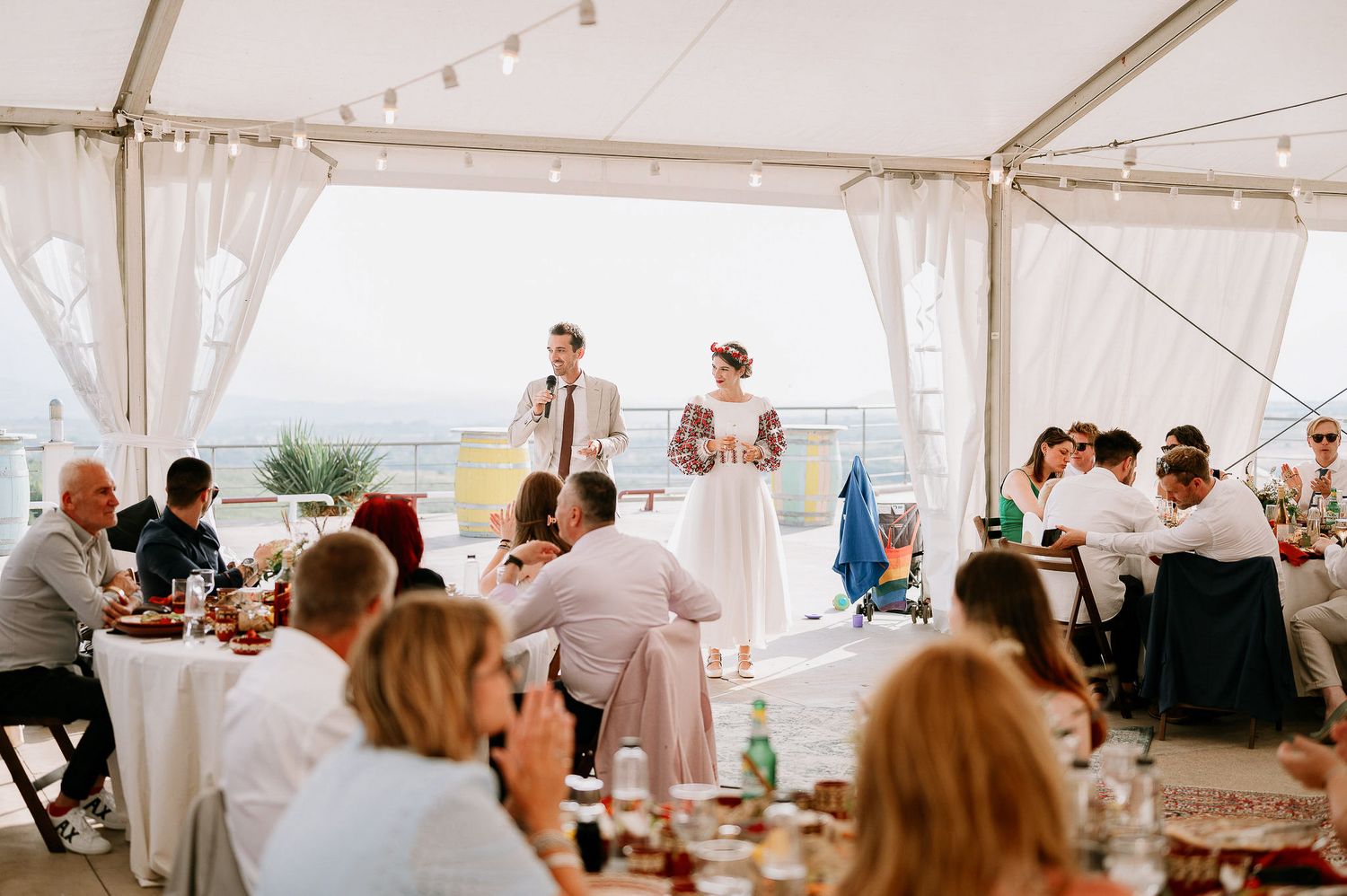 Panoramic view of an elegant tented wedding reception with string lights and white decor.