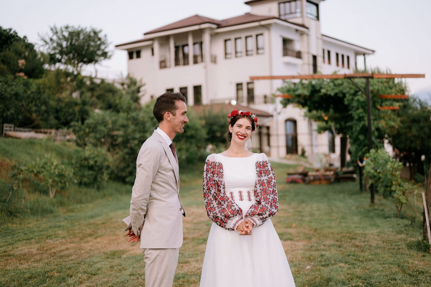 A couple in wedding attire sharing an intimate moment on a grassy hillside.