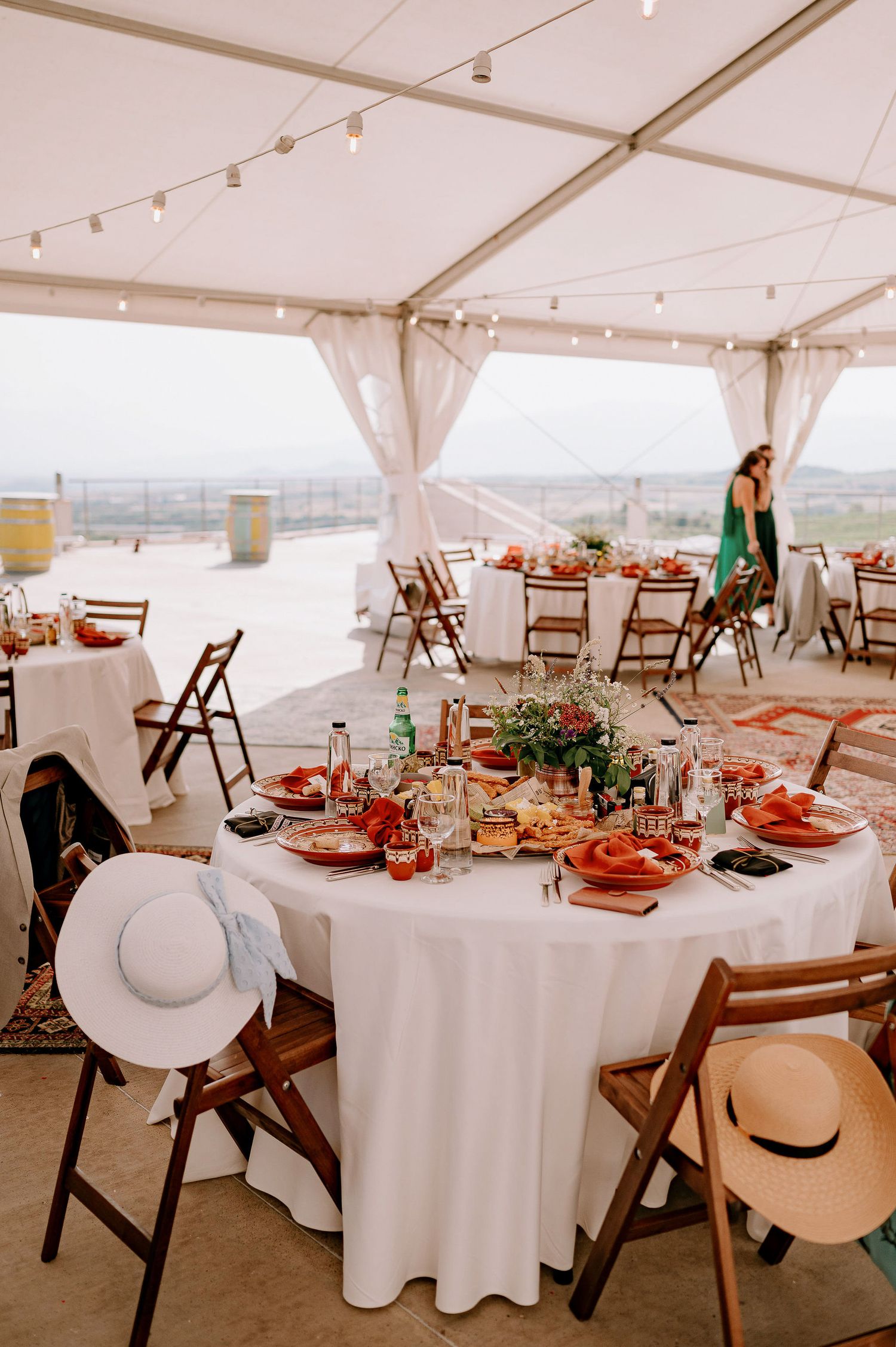 White tent reception venue with round tables and wooden chairs set up for a celebration.