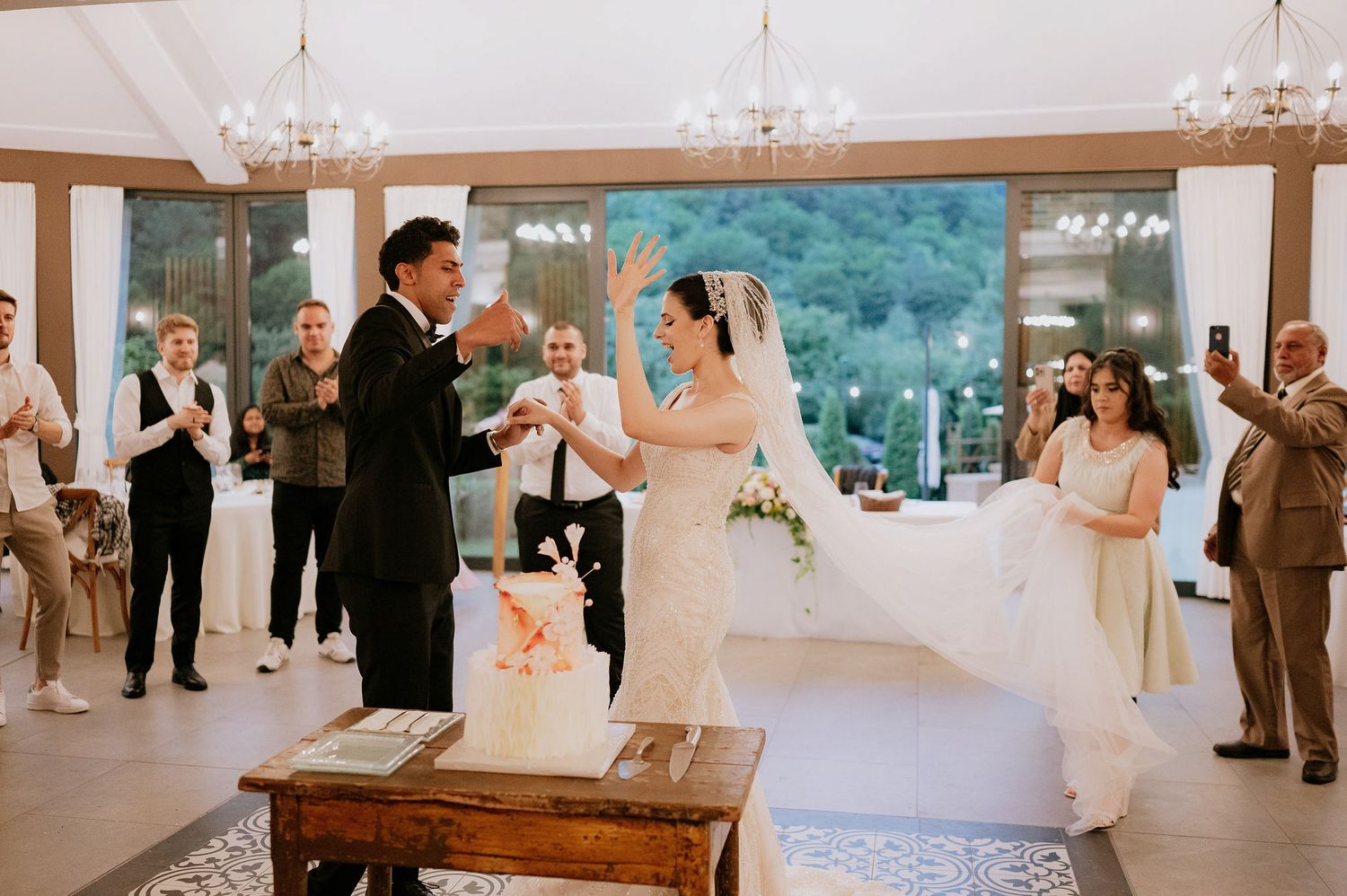 Wedding reception venue features elegant chandeliers and modern decor with large windows.