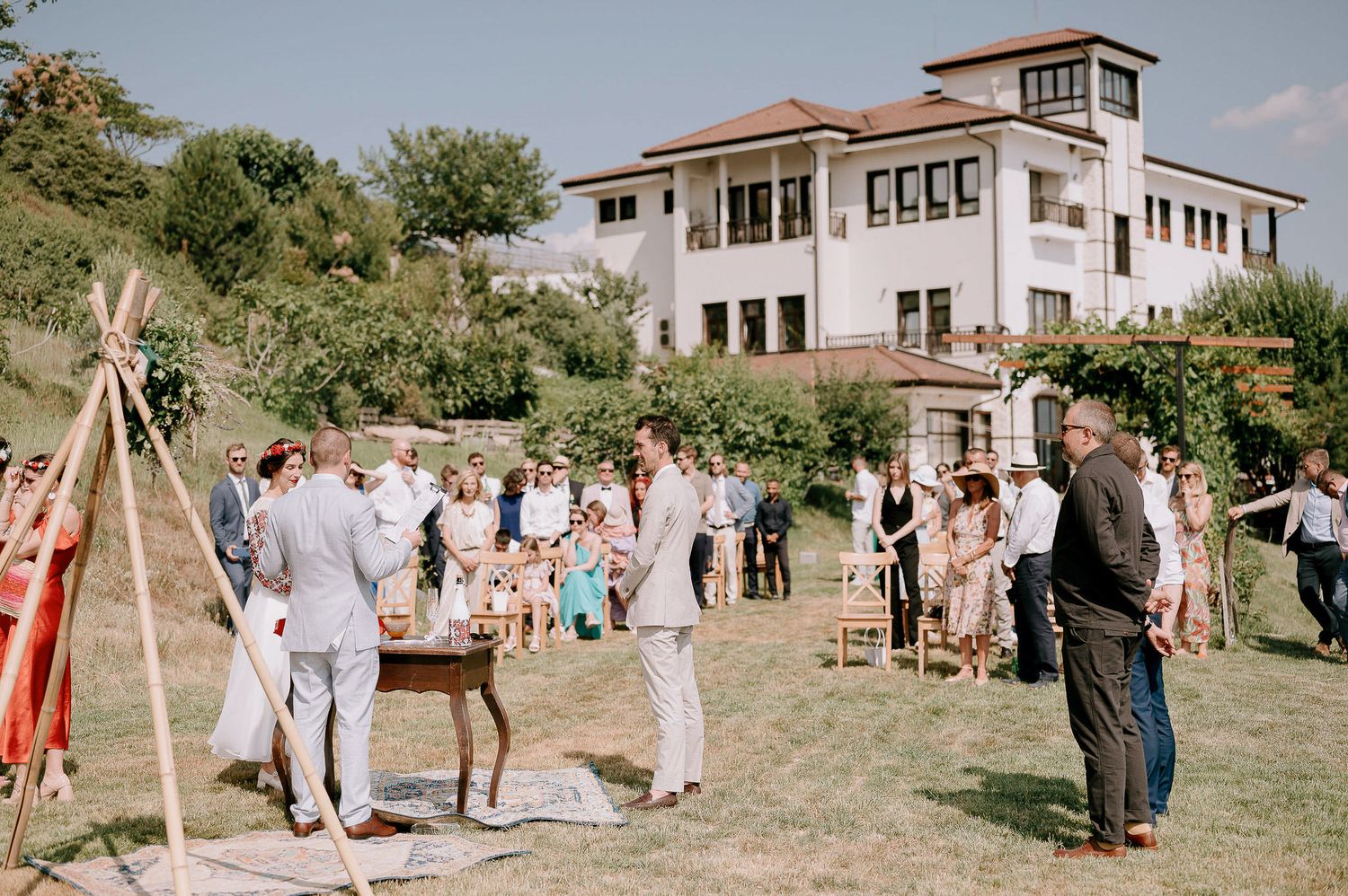 Modern white house with outdoor wedding setup on sprawling lawn.