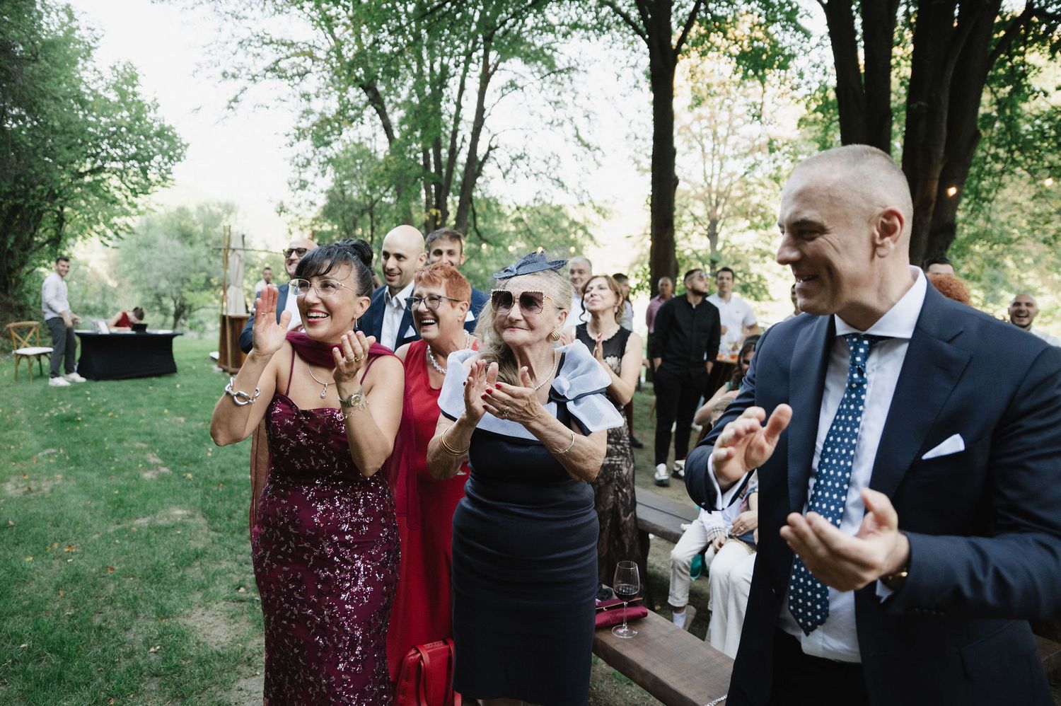 Guests celebrating at an outdoor event surrounded by natural forest scenery.