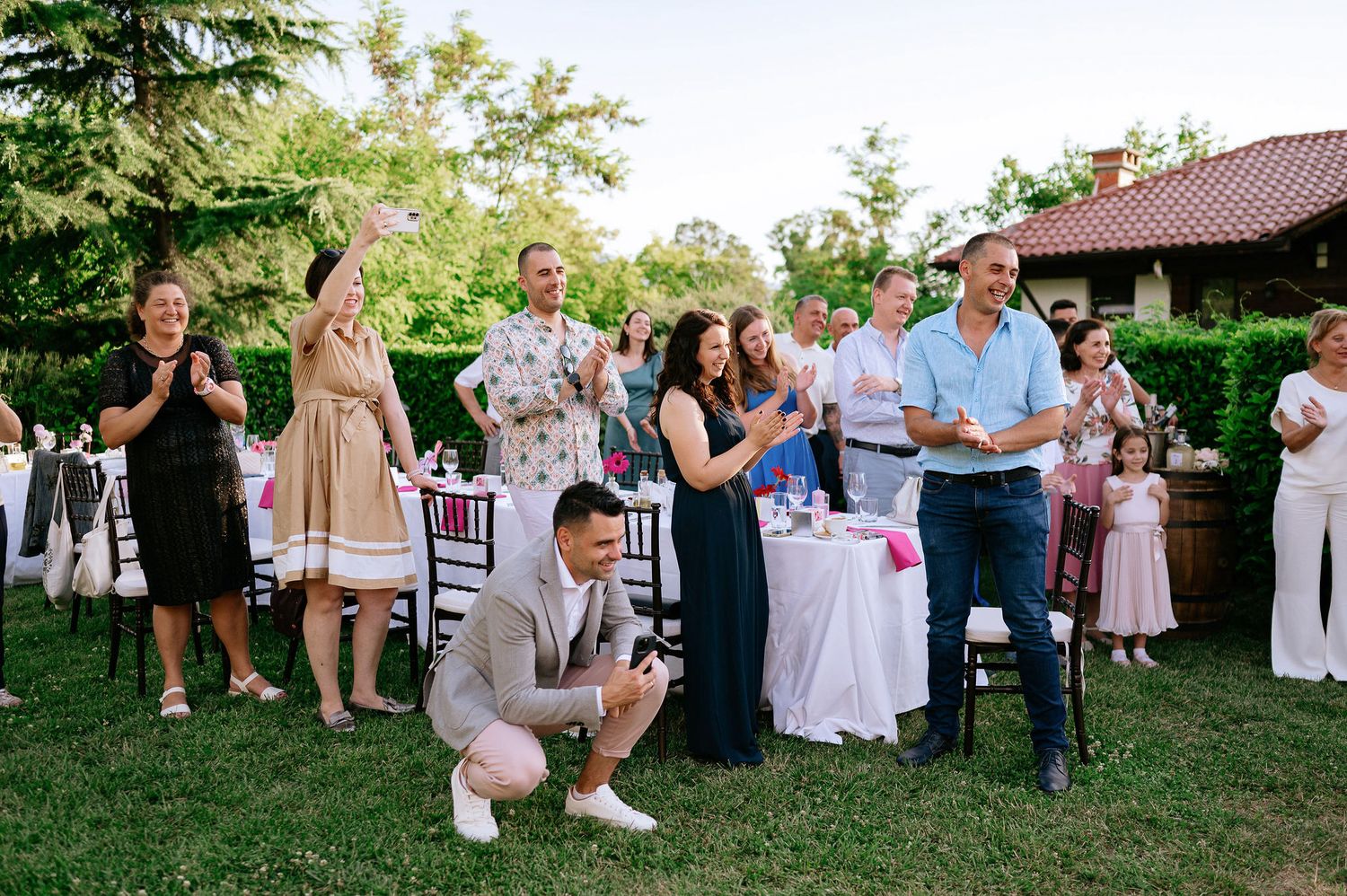 Wedding guests gather outdoors for celebration activities on a summer evening.