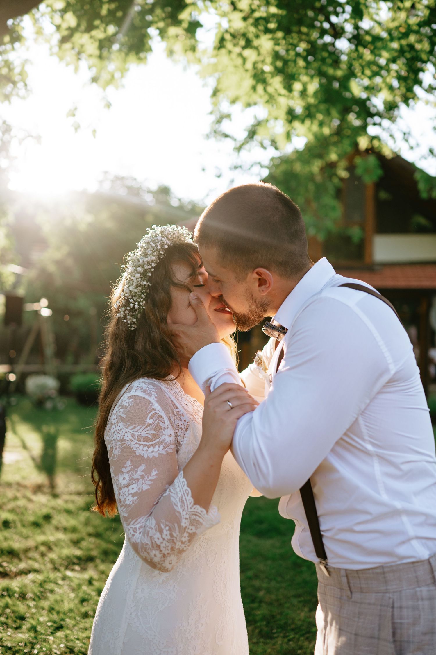 A romantic wedding couple shares intimate moments in a sunlit garden setting.