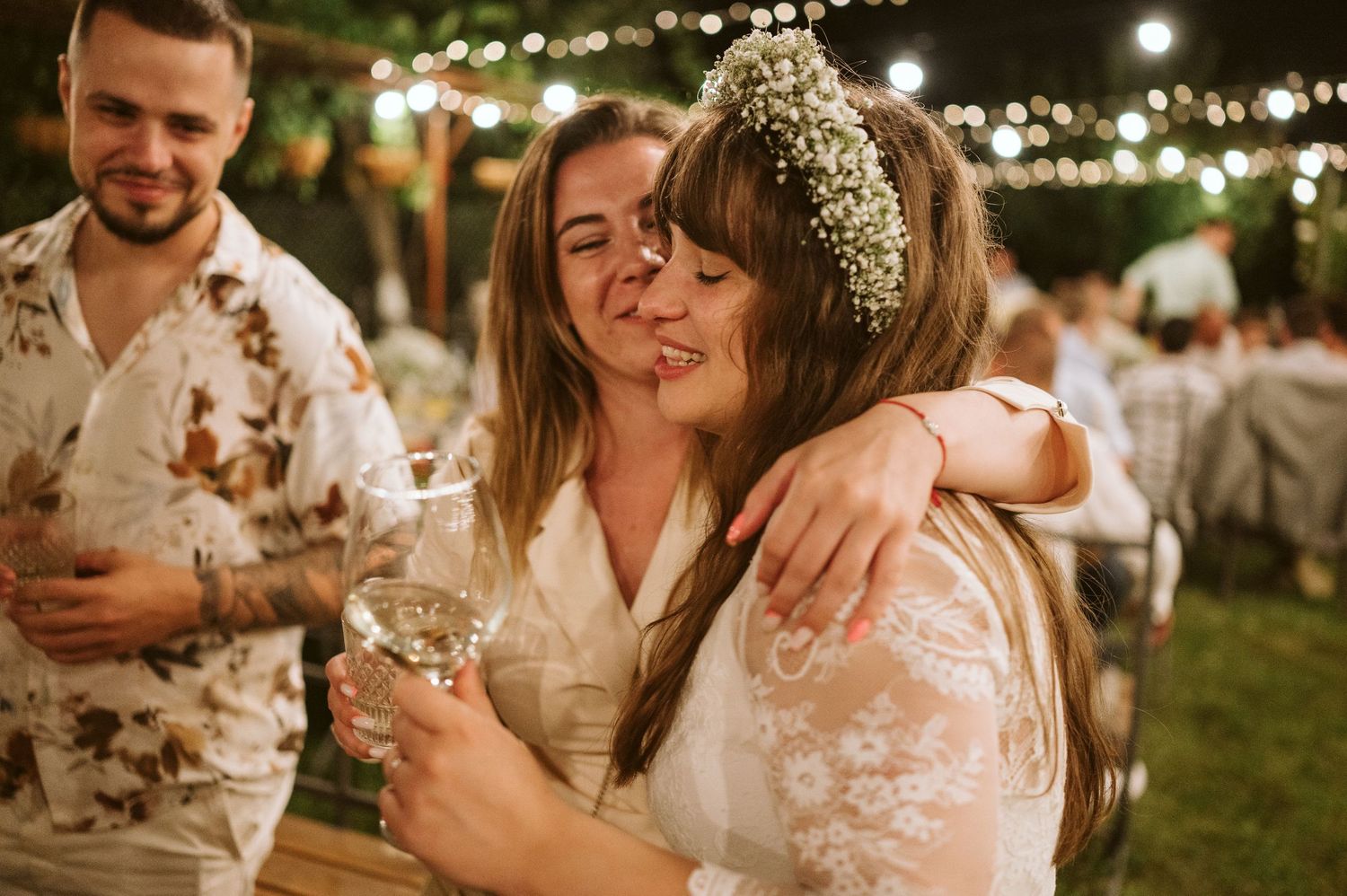 Candid celebration moments at an outdoor wedding reception with string light ambiance.