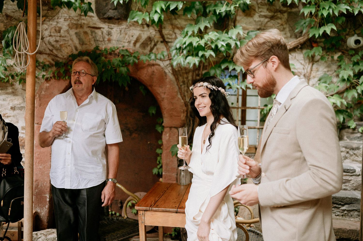 Intimate wedding gathering in a vine-covered courtyard with stone architecture.