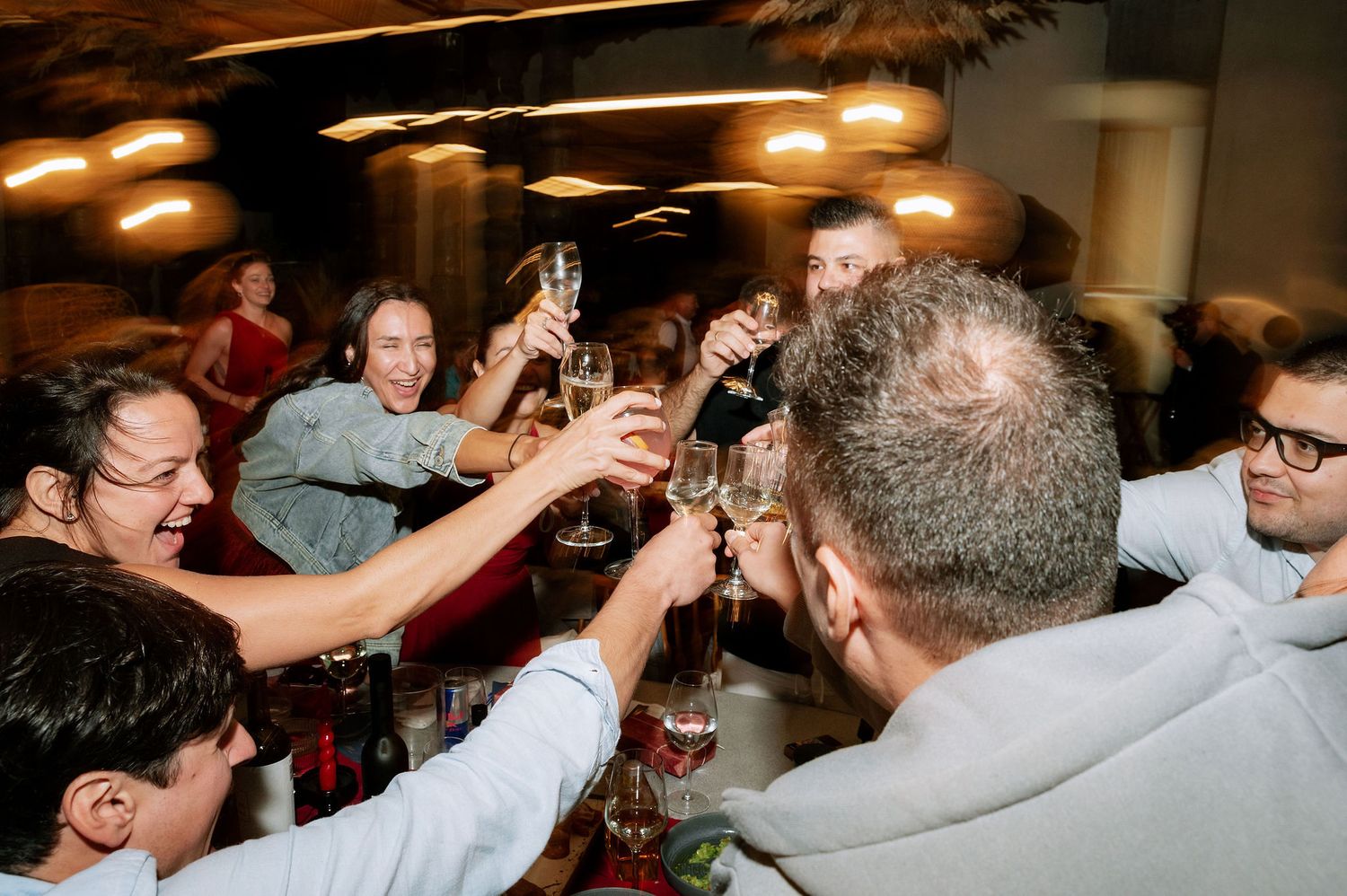 Friends raising glasses in a celebratory toast at an indoor gathering.