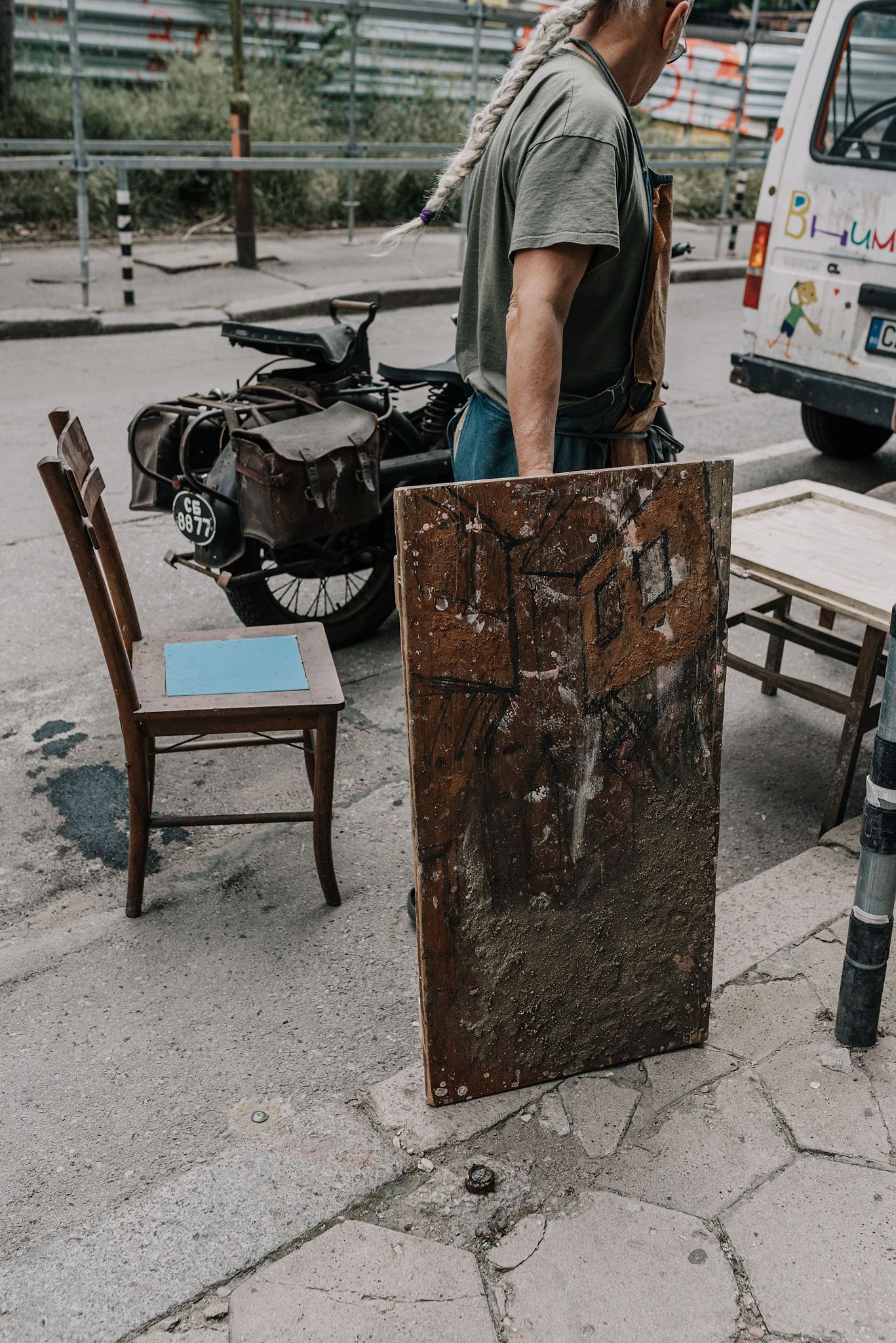 Weathered wooden boards and work materials scattered on concrete ground outdoors.