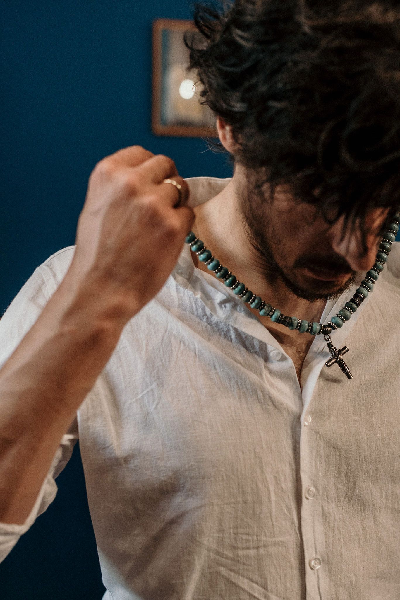 Close-up of necklace and white shirt collar detail.