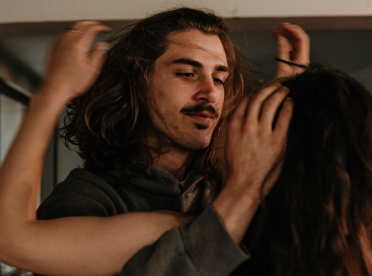 A romantic couple embraces in an intimate moment with warm lighting and moody atmosphere.