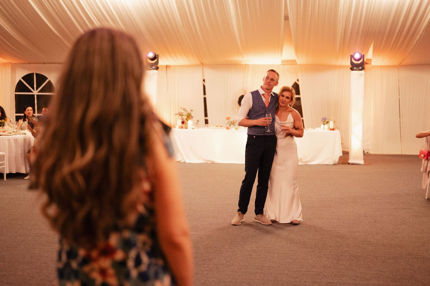 A sequence of wedding reception photos showing people dancing and celebrating under warm lighting in a white tent.