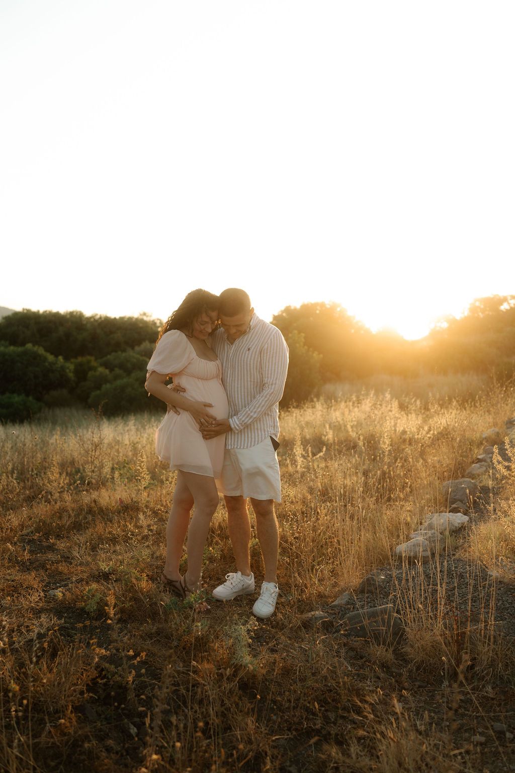 A couple embraces in a golden field during sunset creating a romantic silhouette against the warm evening light.