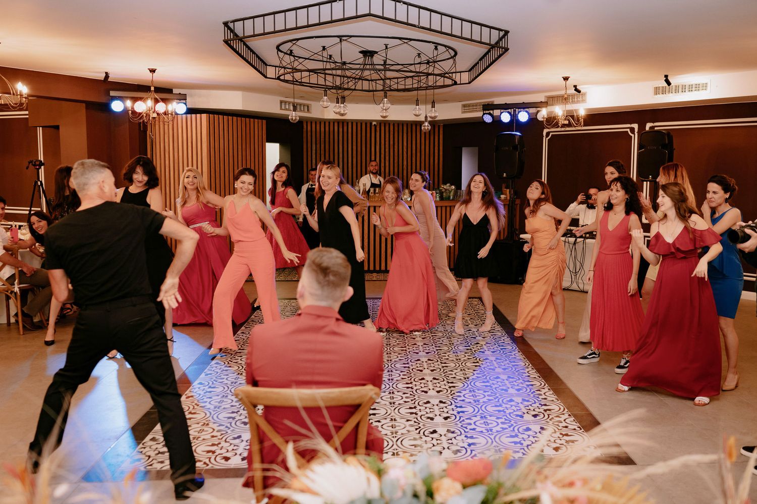 People dancing in a ballroom with colorful dresses and formal attire at an elegant evening event.