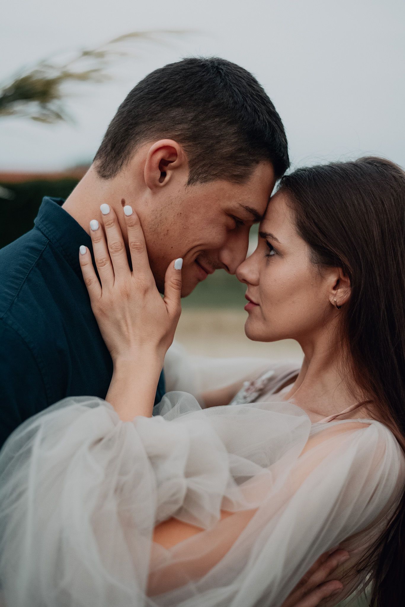 A romantic couple shares an intimate moment in soft lighting while wearing wedding attire.