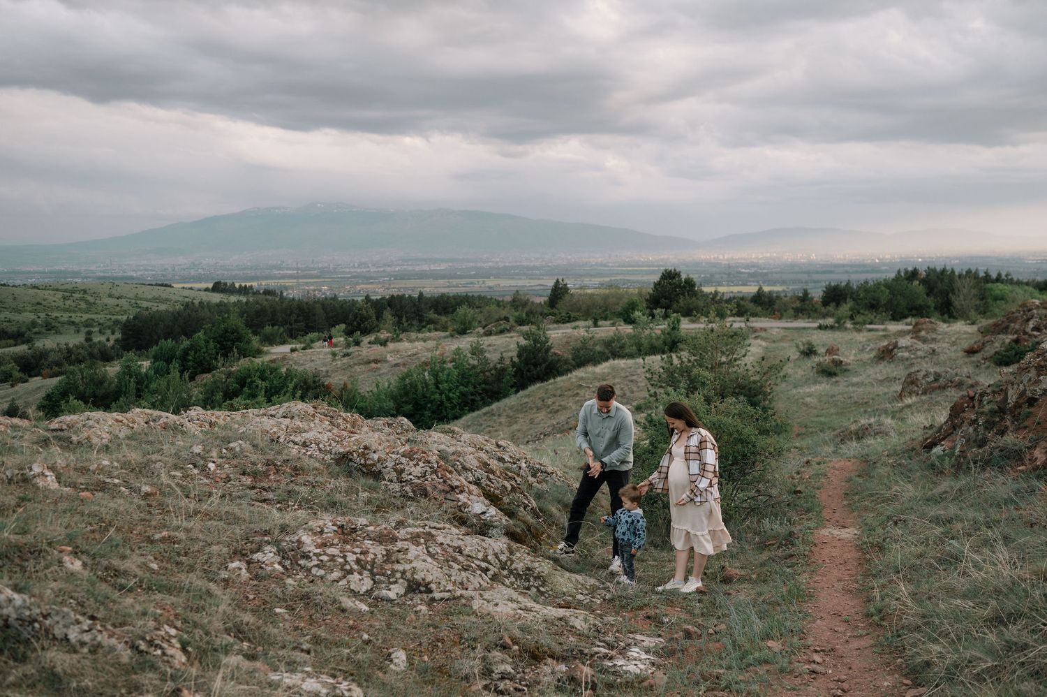 A series of panoramic landscape photos showing couples walking on a rugged mountain trail under cloudy skies.
