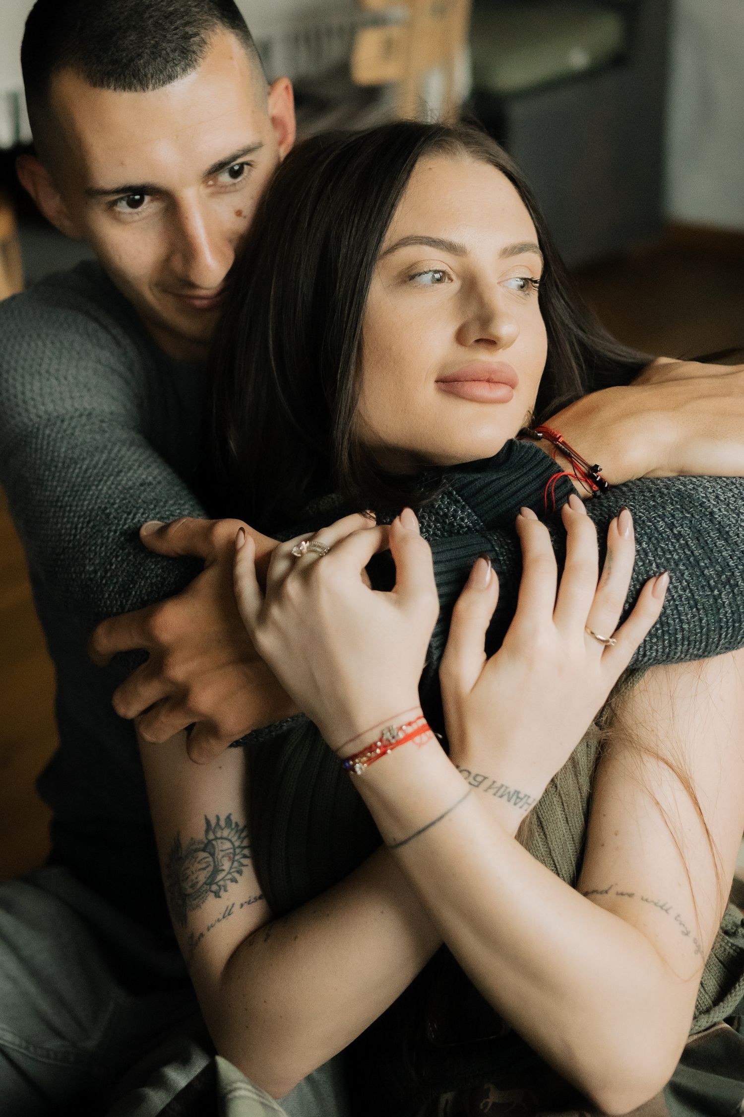 A couple embraces intimately in a series of romantic photos showing tattoos and red bracelets.