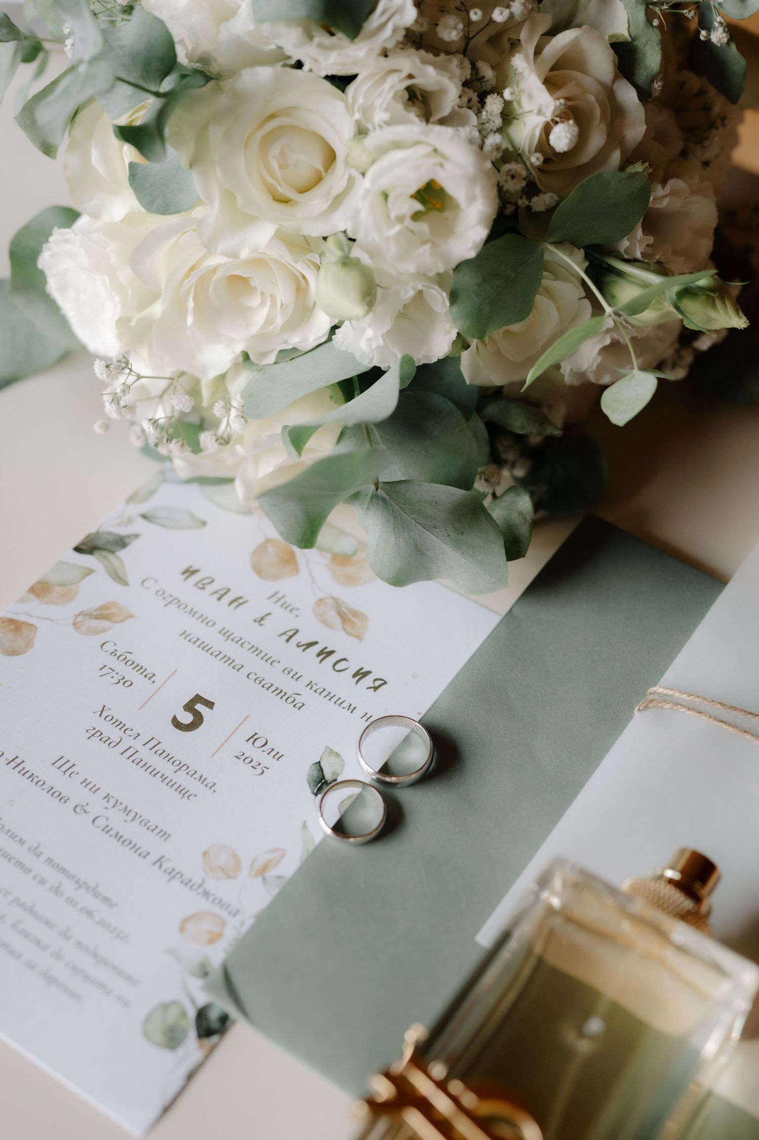 Elegant wedding stationery with white roses and eucalyptus on a sage green background.