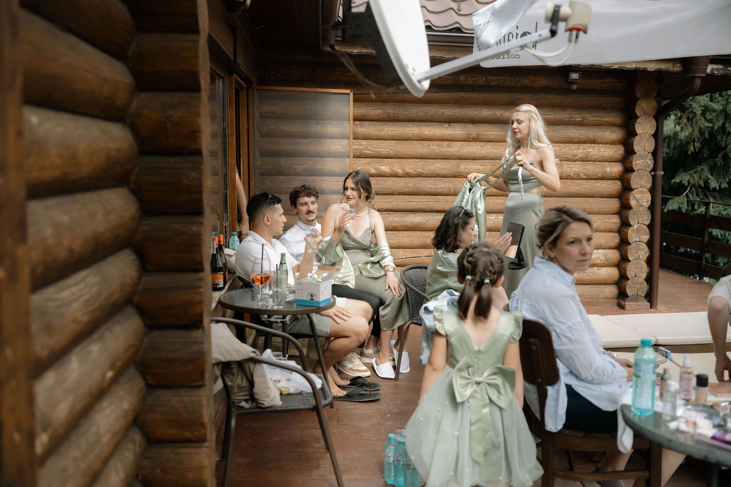 Wedding party lounges casually against wooden cabin exterior in coordinated mint green robes.