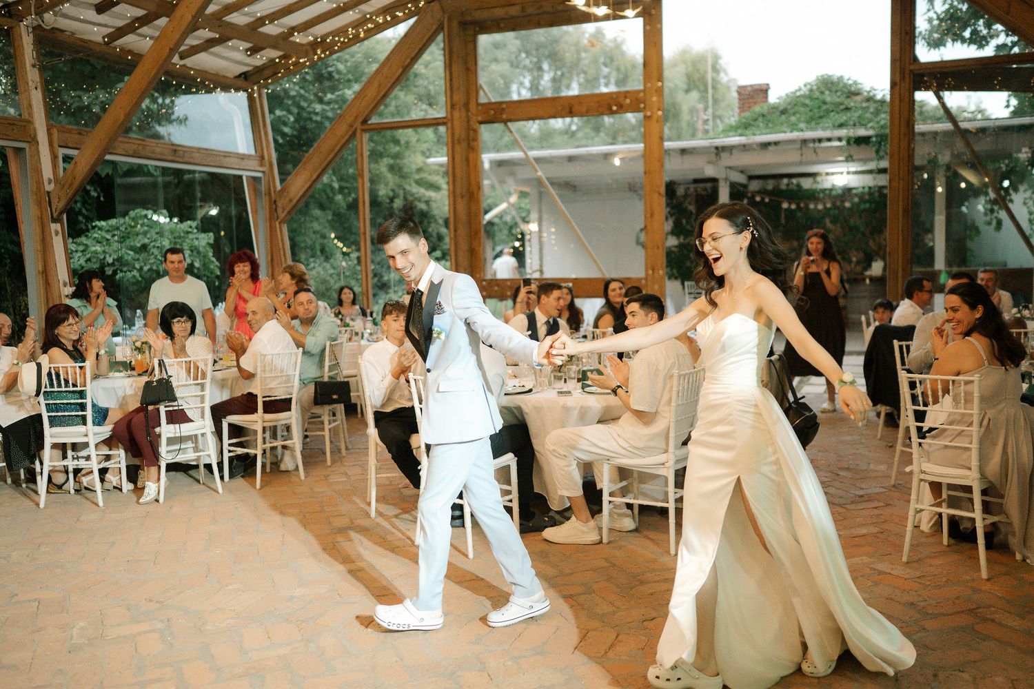 Wedding guests dancing and celebrating on a rustic wooden dance floor at an outdoor reception venue.