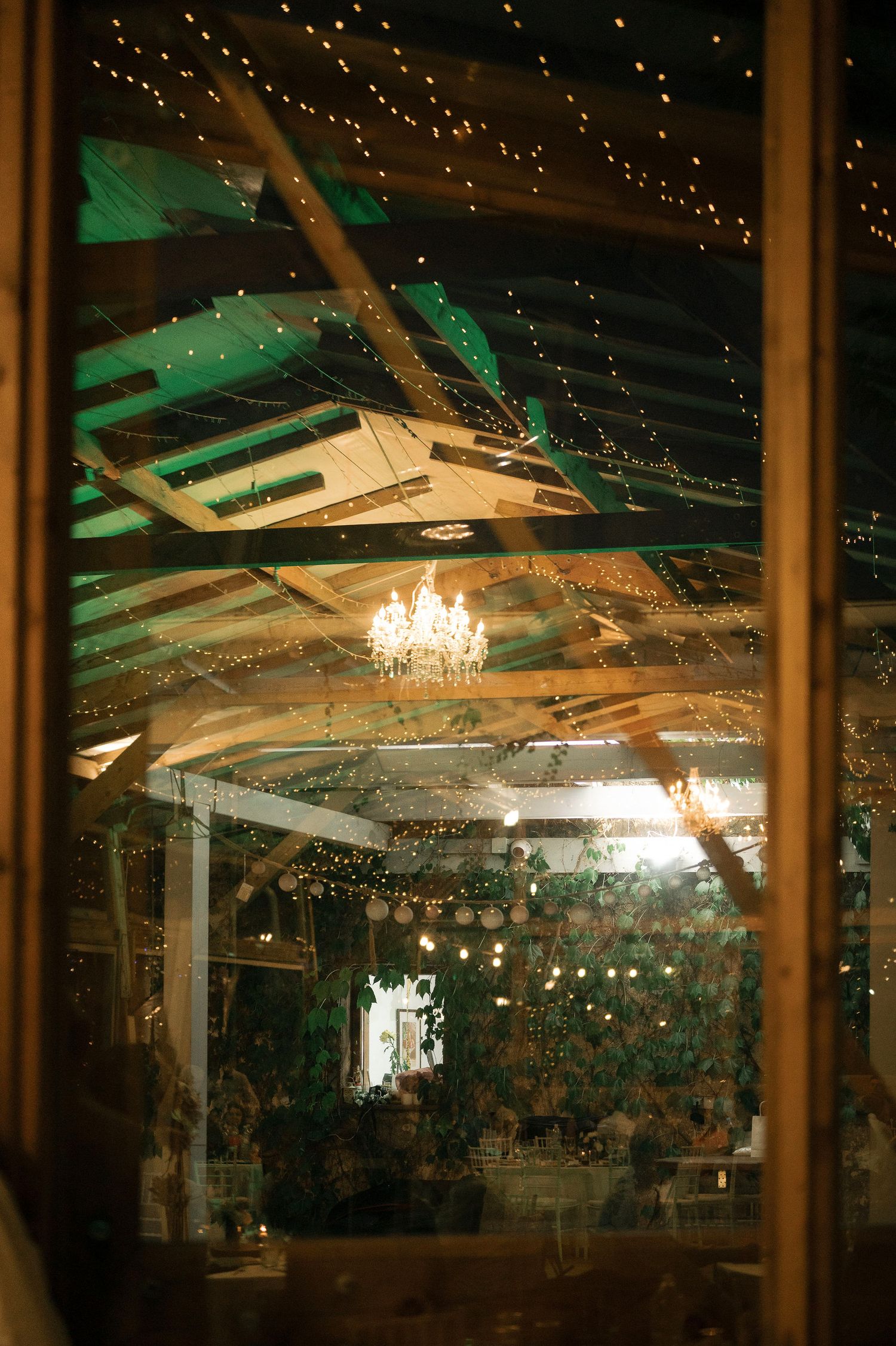Elegant wedding venue interior with twinkling string lights and crystal chandeliers creating a romantic atmosphere.