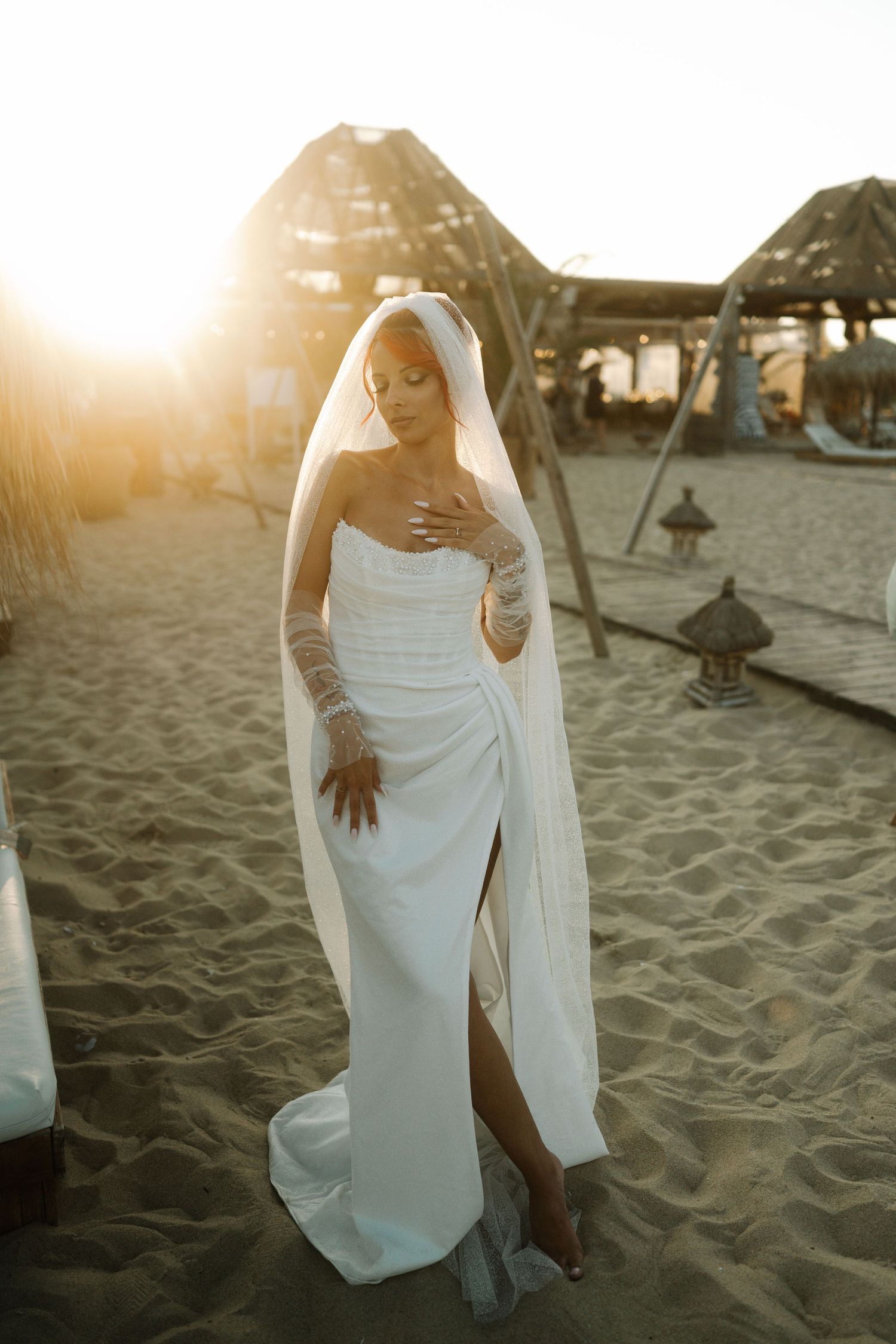 Romantic sunset beach wedding photos with bride in flowing white dress and veil walking on sandy shore.