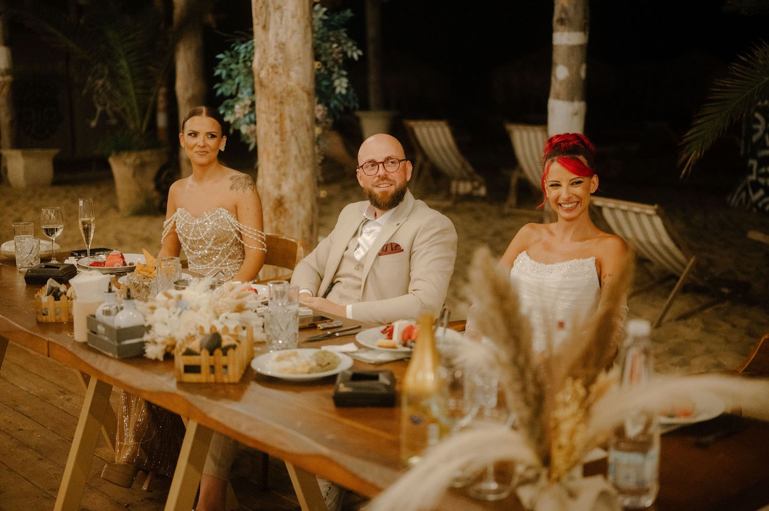 Elegant wedding reception table settings with glowing candles and floral centerpieces in a rustic venue.