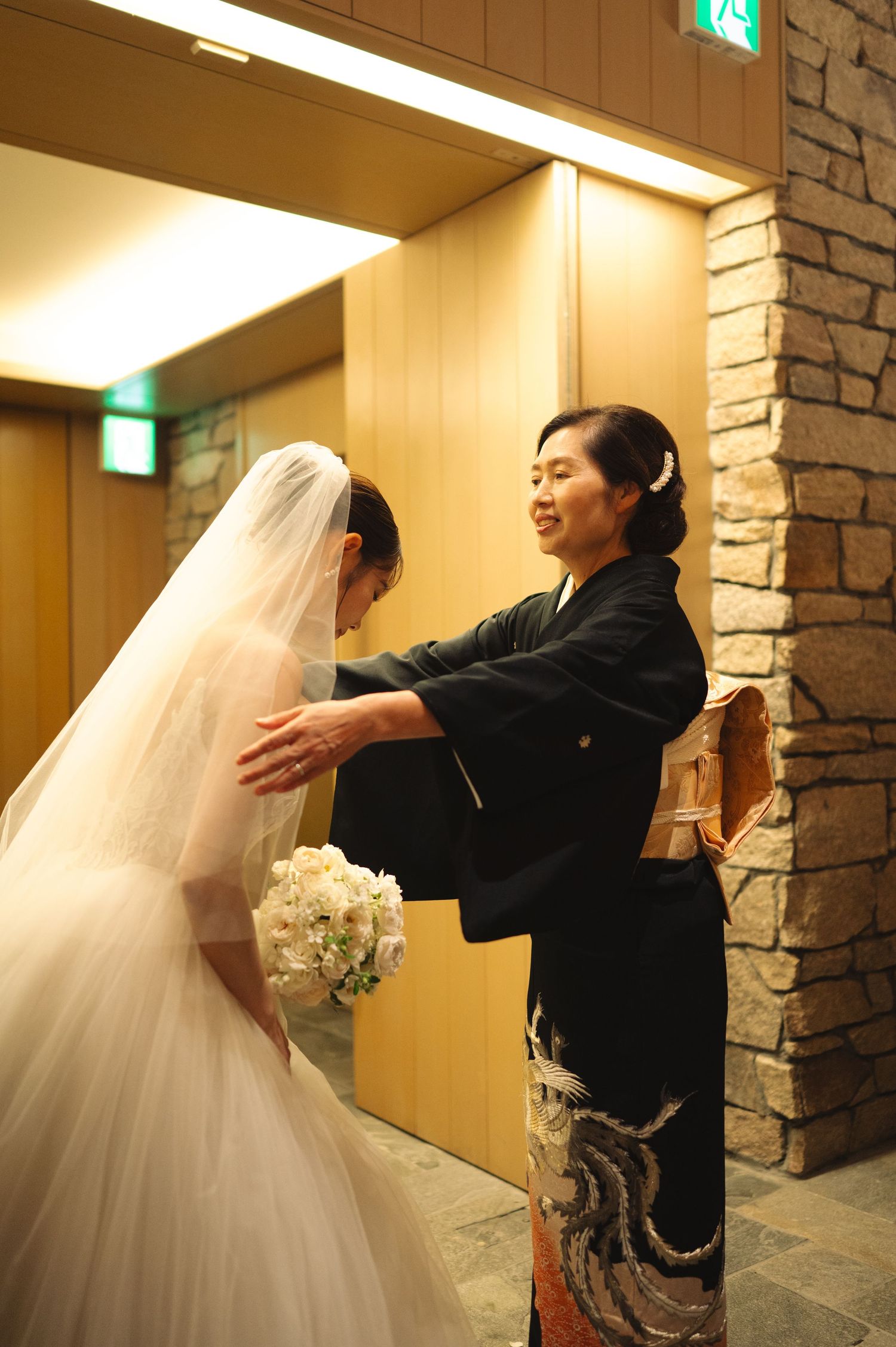 Emotional wedding moment captured in hallway as bride greets guests.