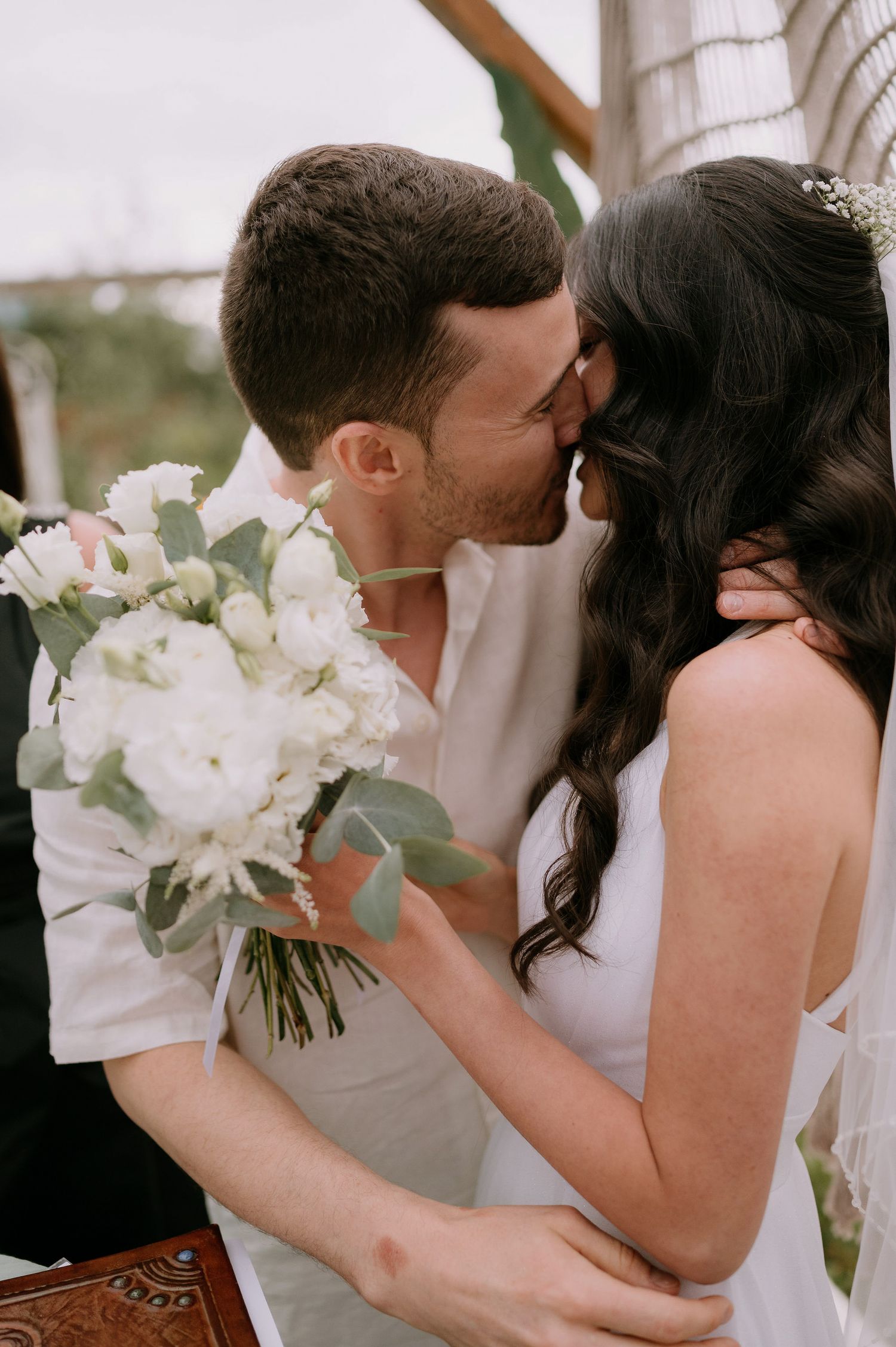Romantic wedding moment with white floral bouquet featuring eucalyptus leaves.