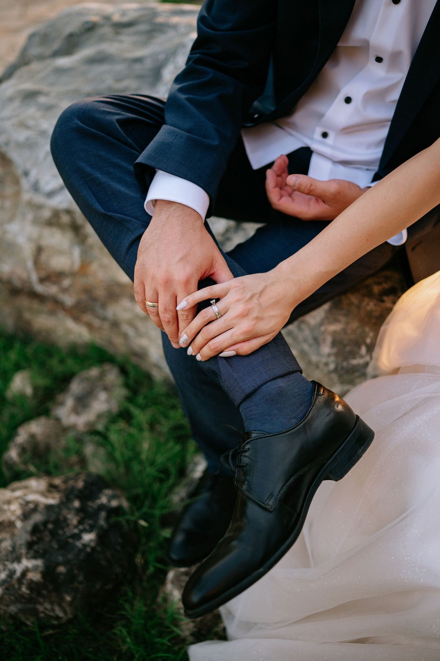 Close-up detail shot of formal wedding shoes and dress hem on natural stone.