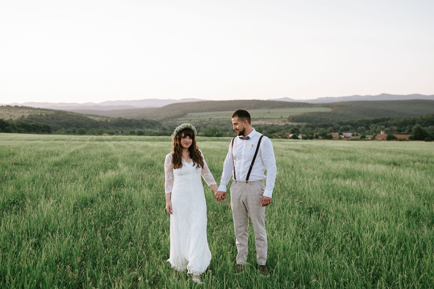 Romantic couple strolling through a serene meadow during sunset.