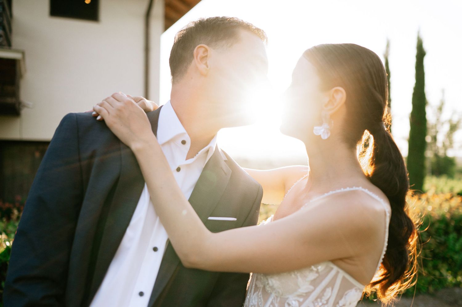 Sunlit wedding portrait capturing a romantic dance moment against a garden landscape.