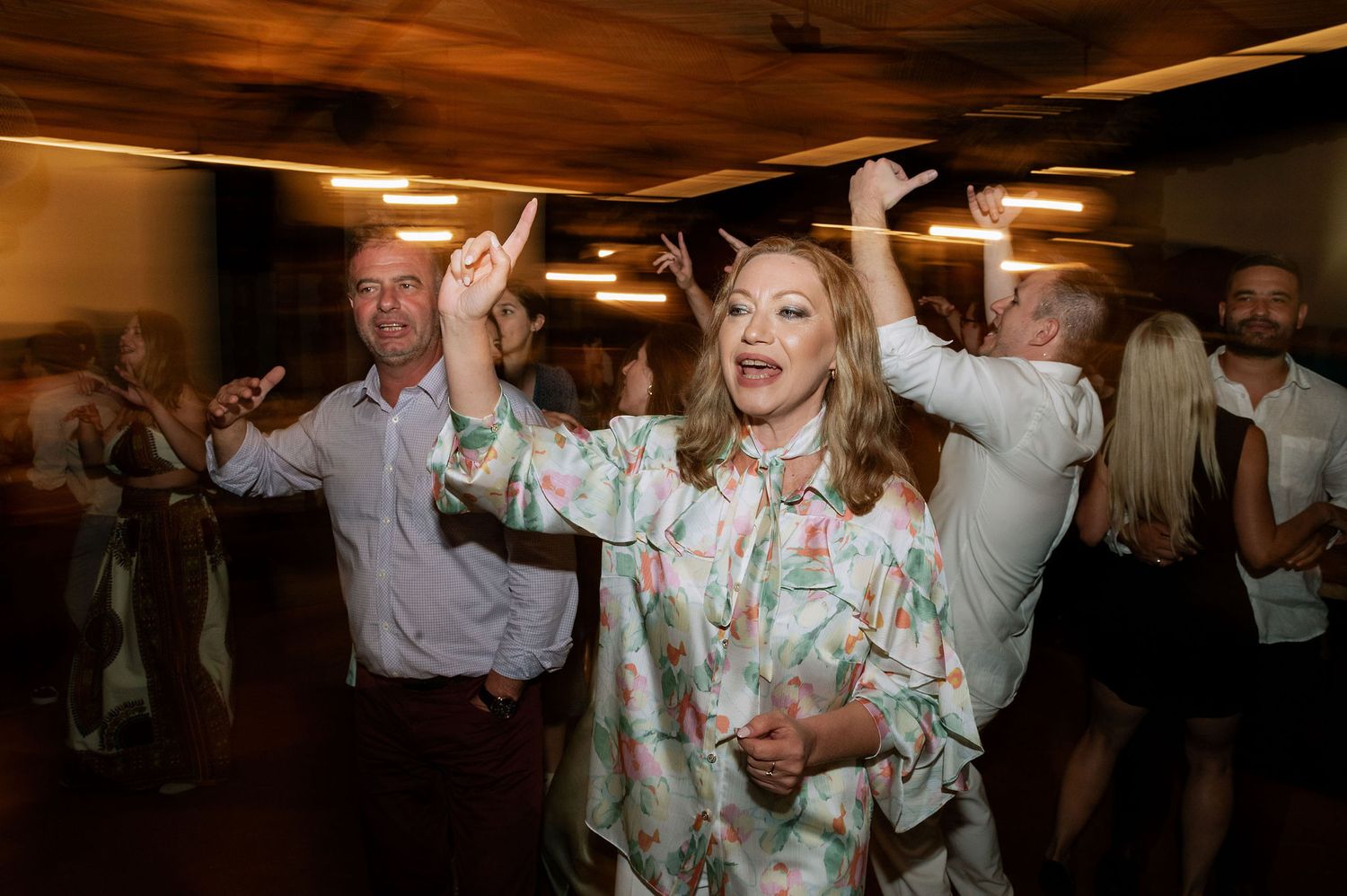 Wedding reception dance floor with guests celebrating under warm ambient lighting.