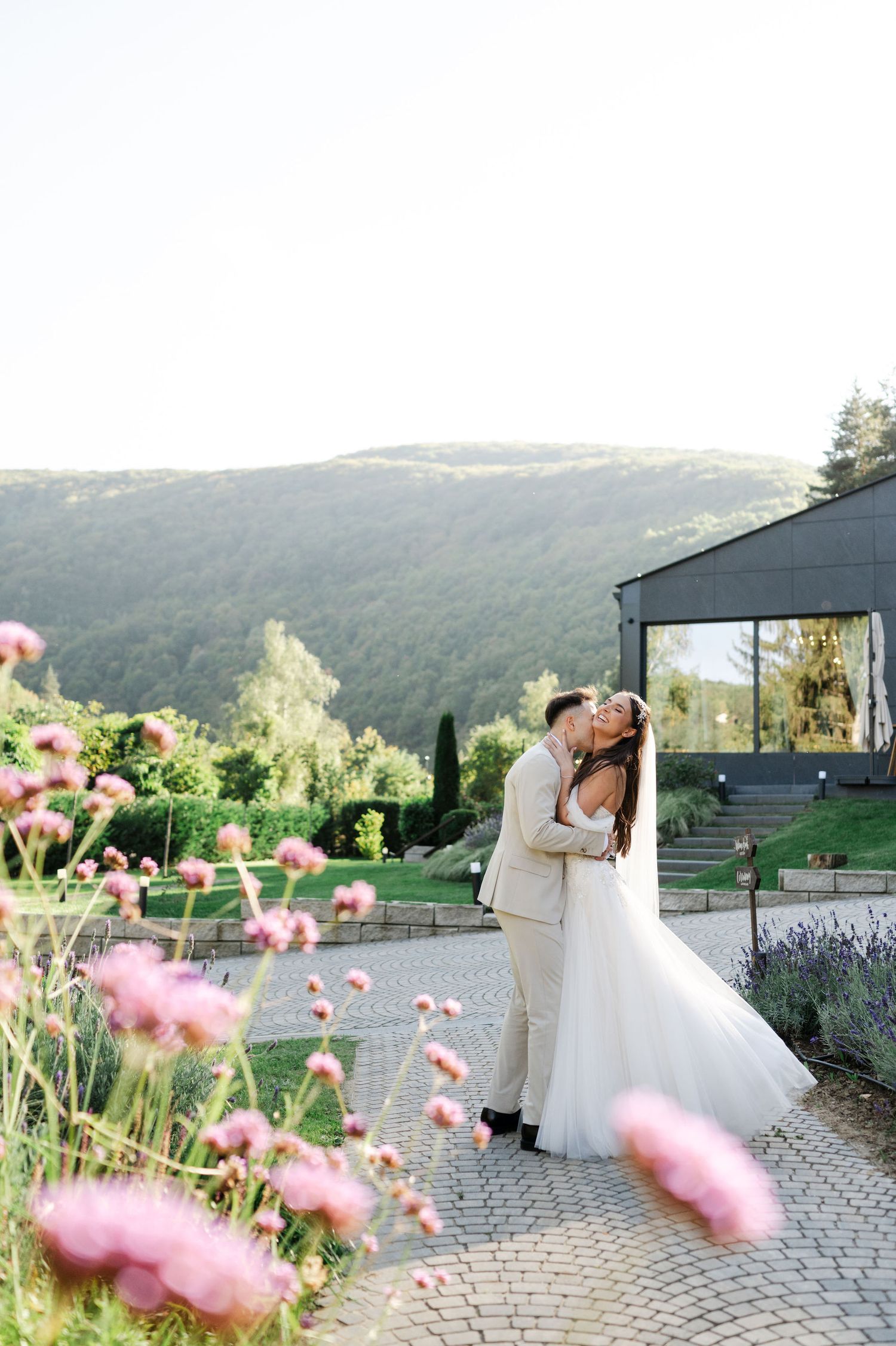 Wedding photography sequence with pink flowers framing a romantic moment on a mountain overlook.