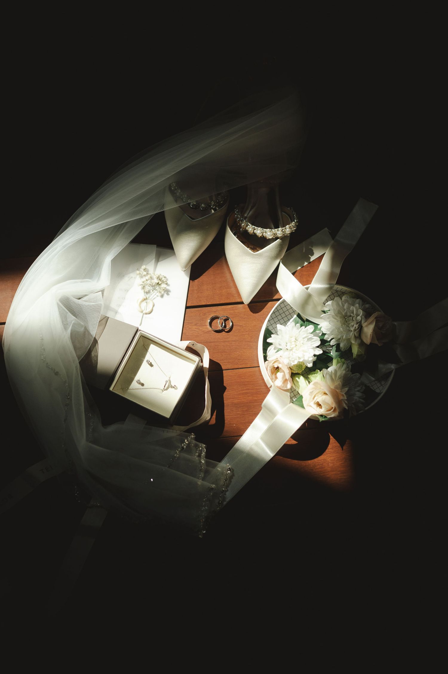 Artistic overhead shot of wedding details including rings and paper in moody lighting.
