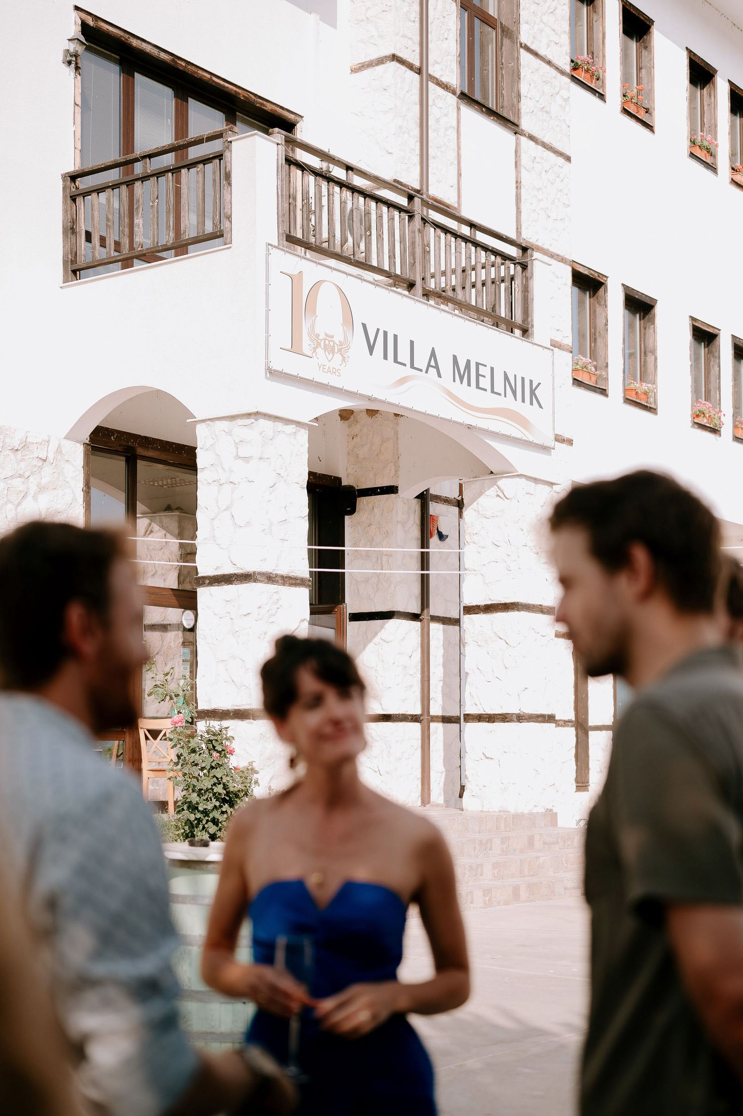 Exterior view of Villa Melnik building with white walls and wooden balconies.